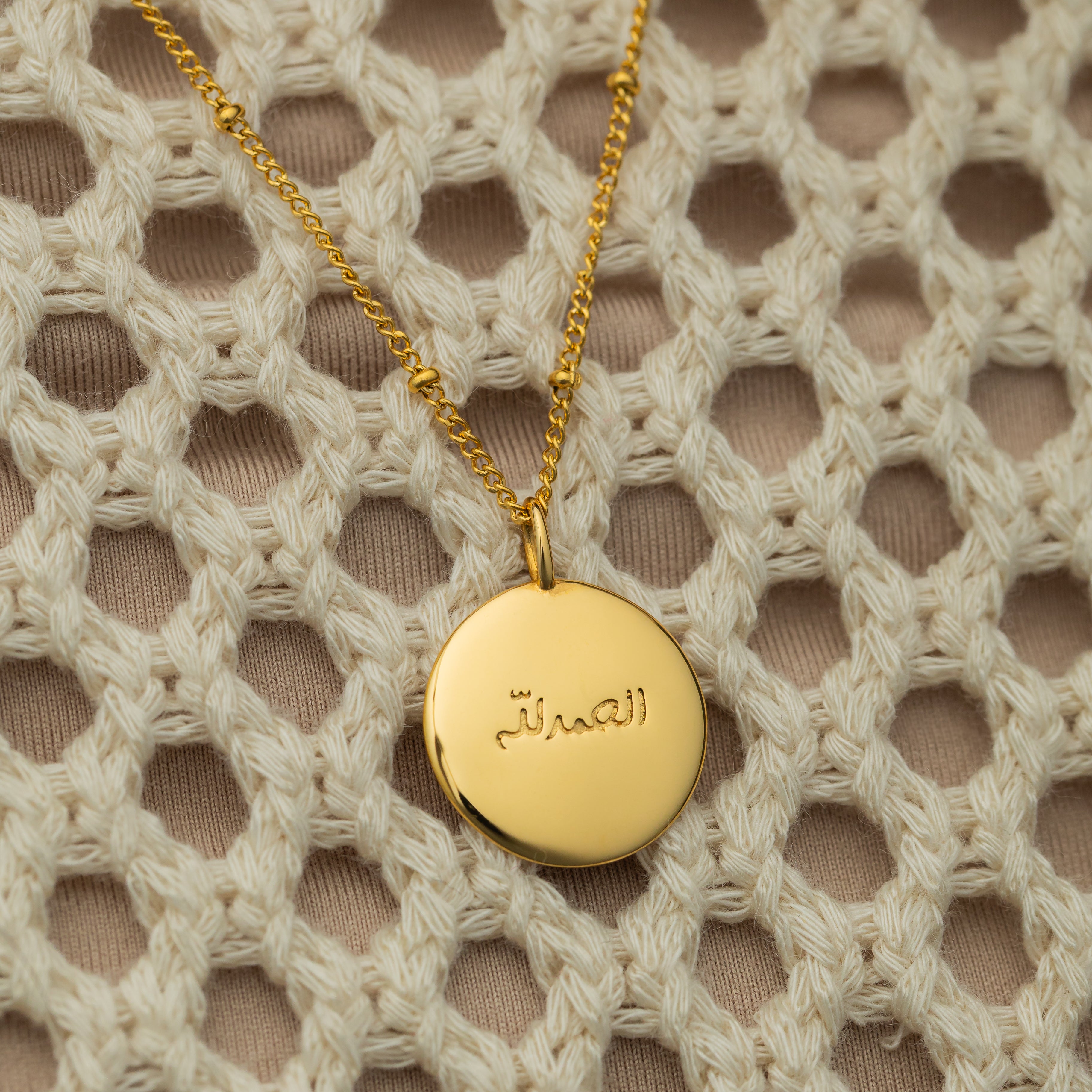 Close-up of the gold charm on a delicate chain, emphasizing its hypoallergenic properties.