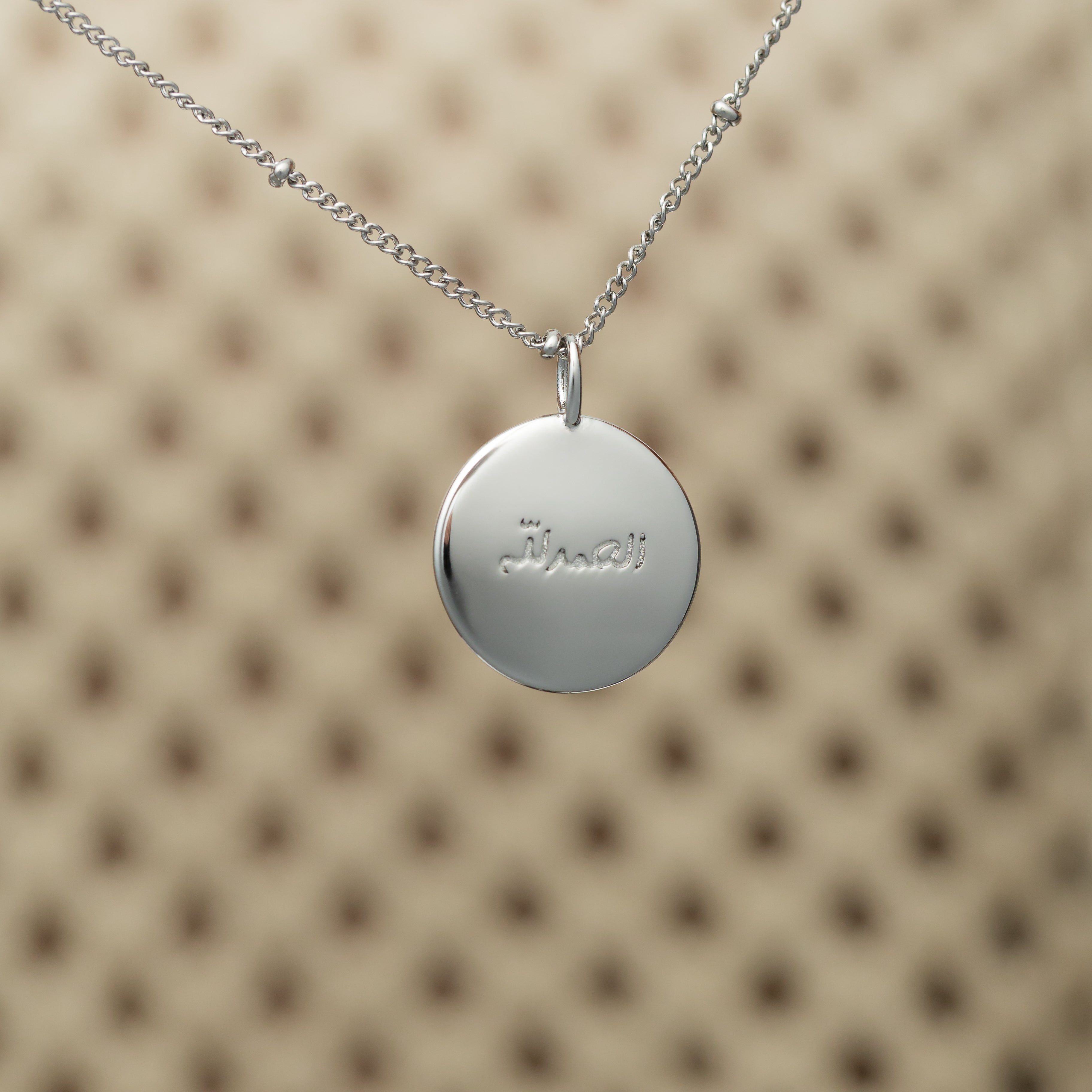 Close-up of the gold charm on a delicate chain, emphasizing its hypoallergenic properties.