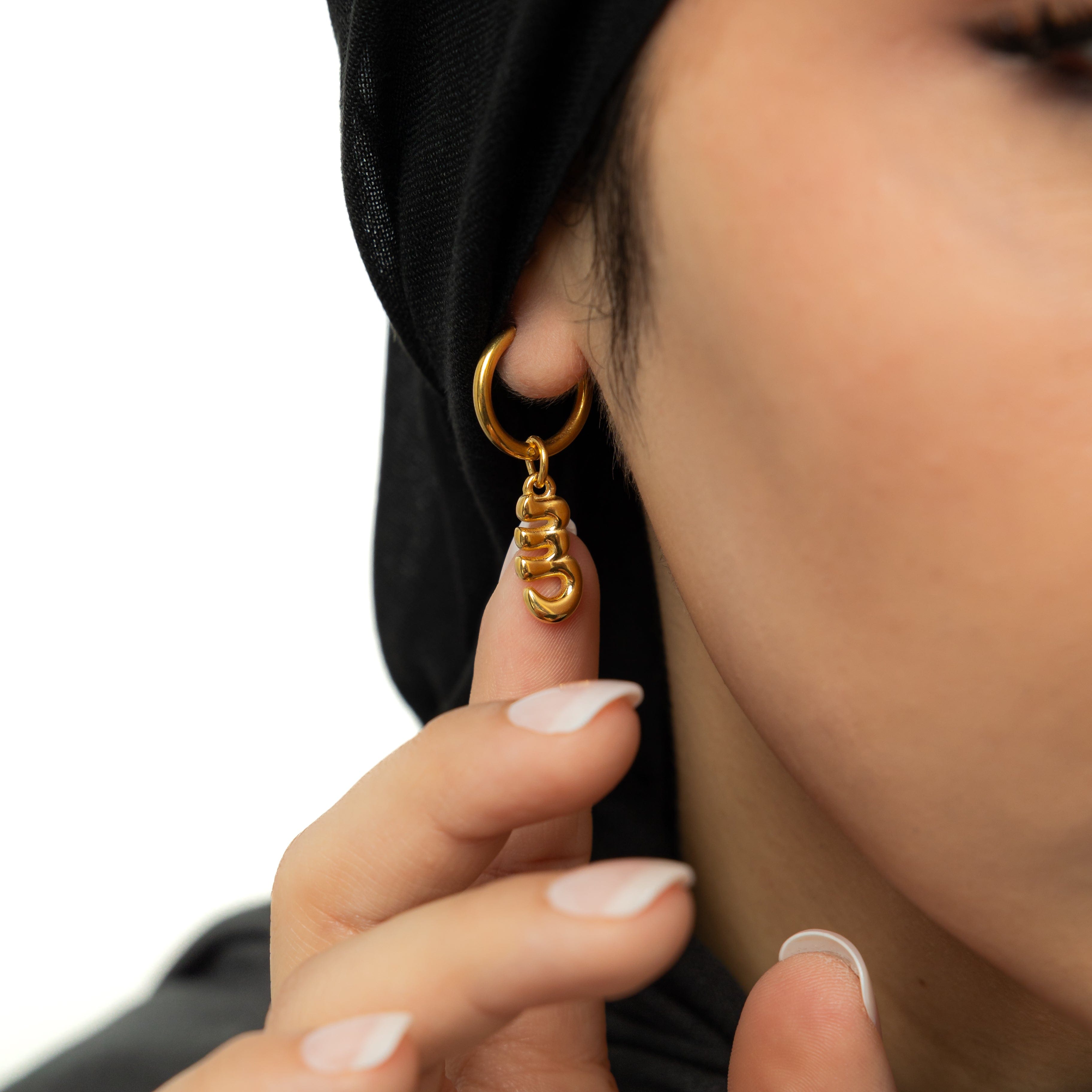 Side angle of personalized earrings worn on ear to highlight shine and size