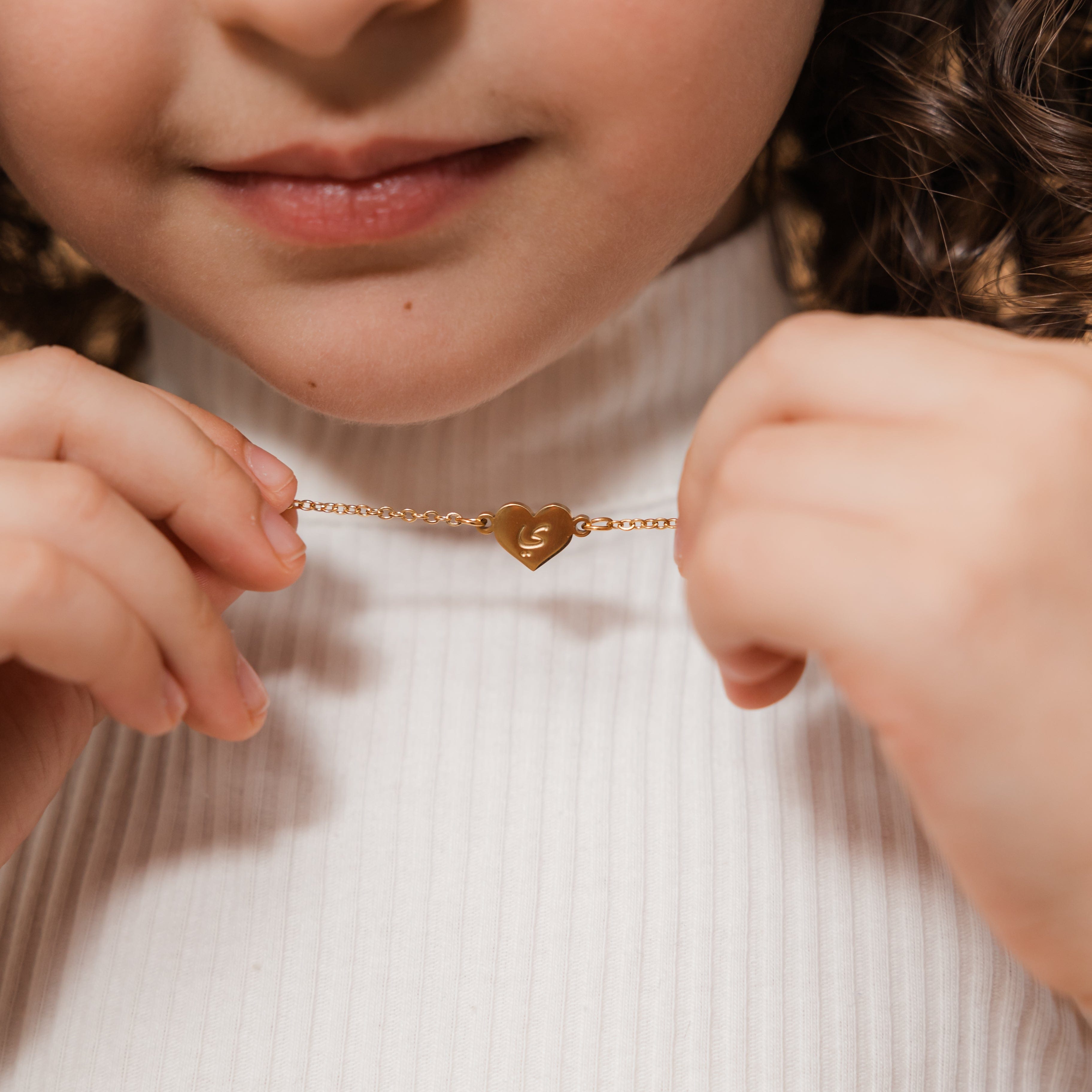 The Arabic letter heart necklace displayed on a young girl, highlighting its delicate design.