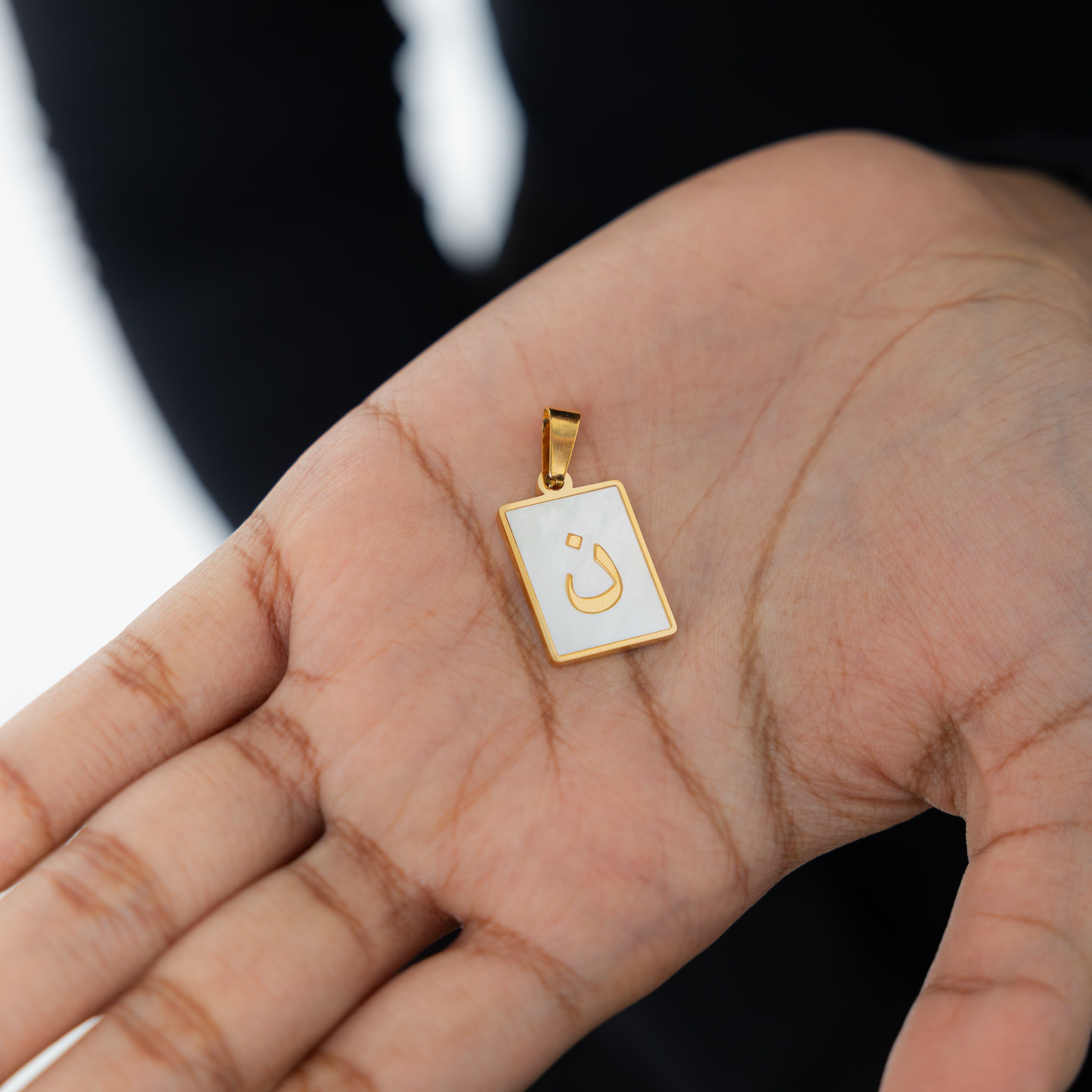 Nominal velvet pouch holding Arabic letter charms, perfect for gifting or personal use.