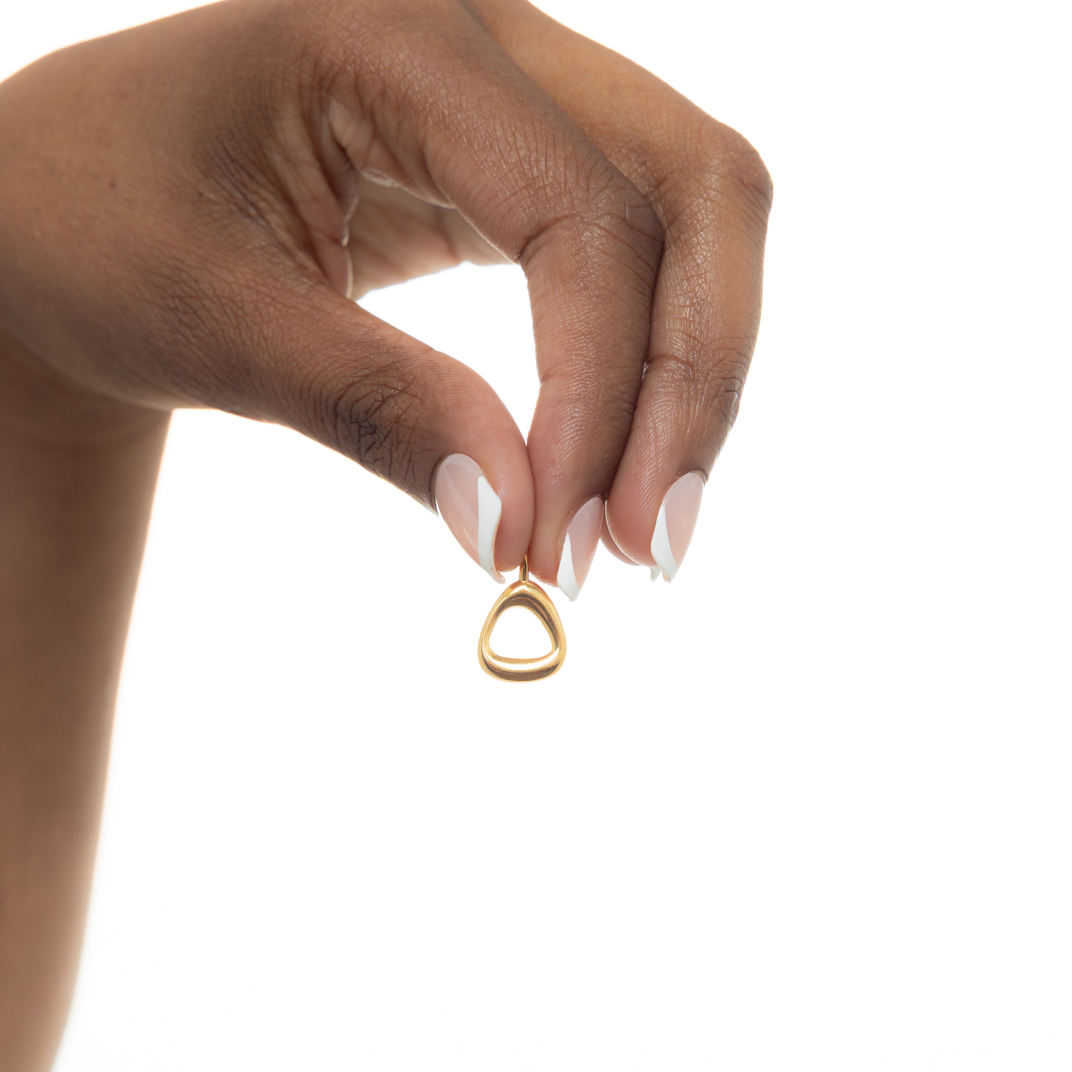 A hand wearing gold plated number charms, illustrating their compatibility with various styles.
