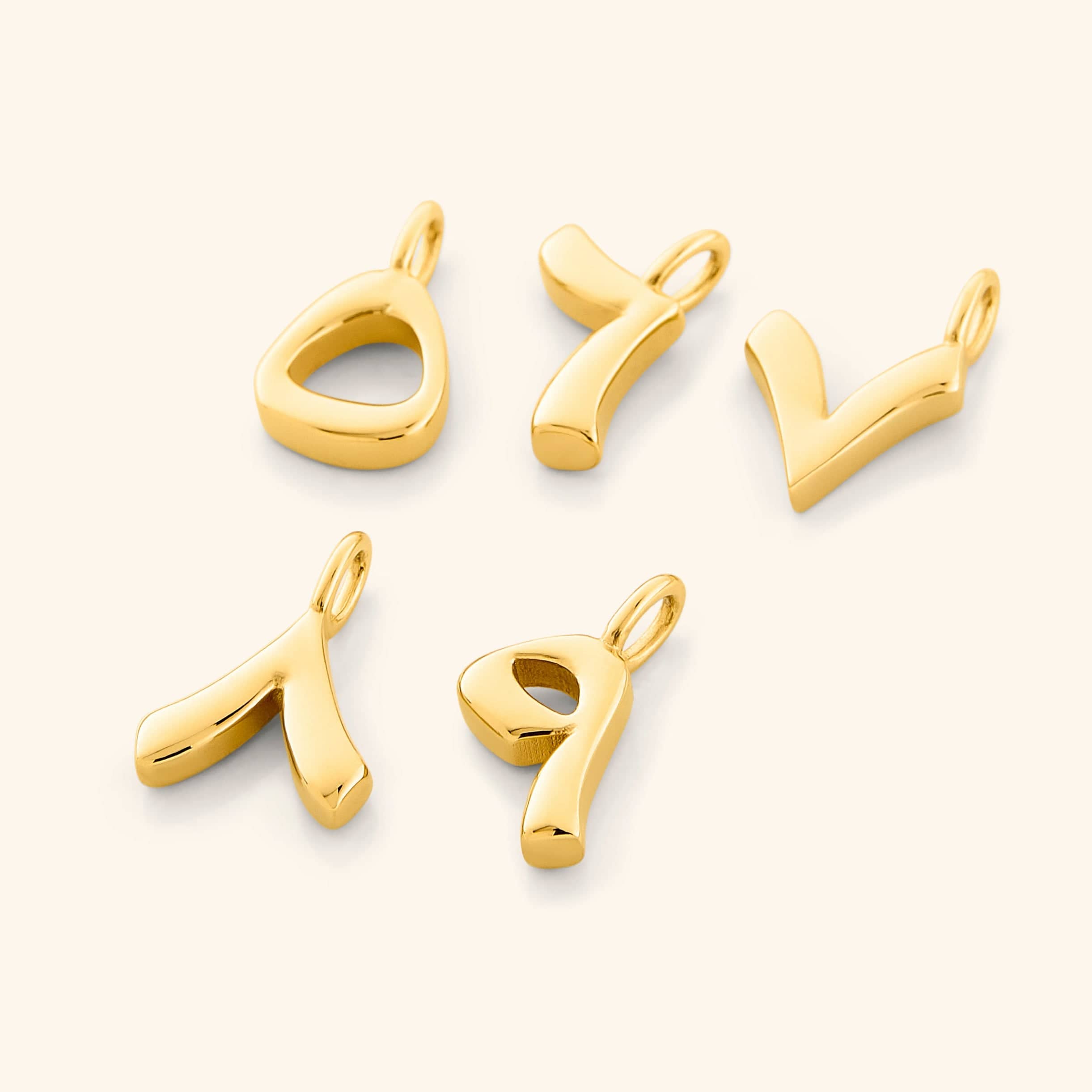 A hand wearing gold plated number charms, illustrating their compatibility with various styles.
