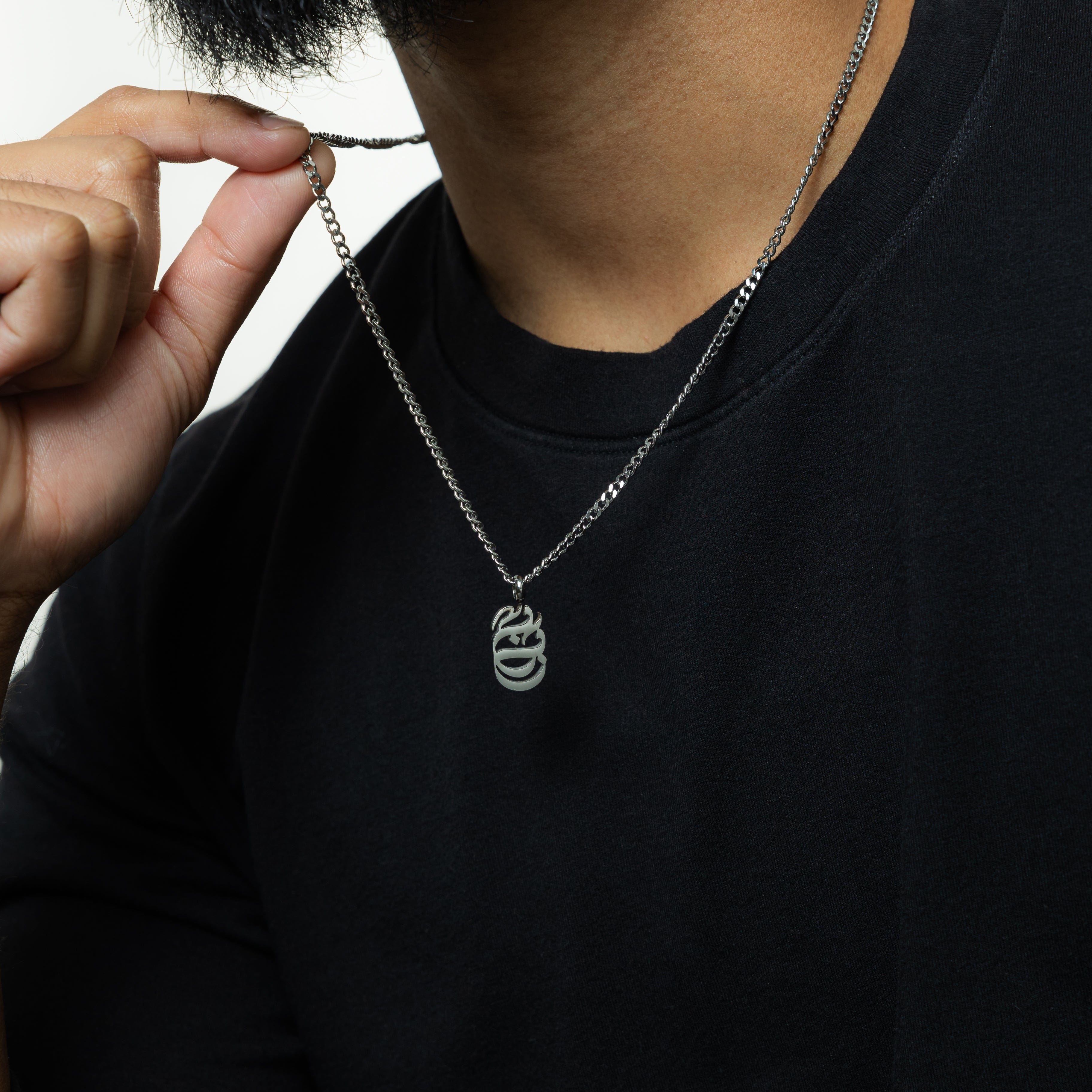 Baba Oval Arabic Calligraphy Necklace displayed on a wooden table