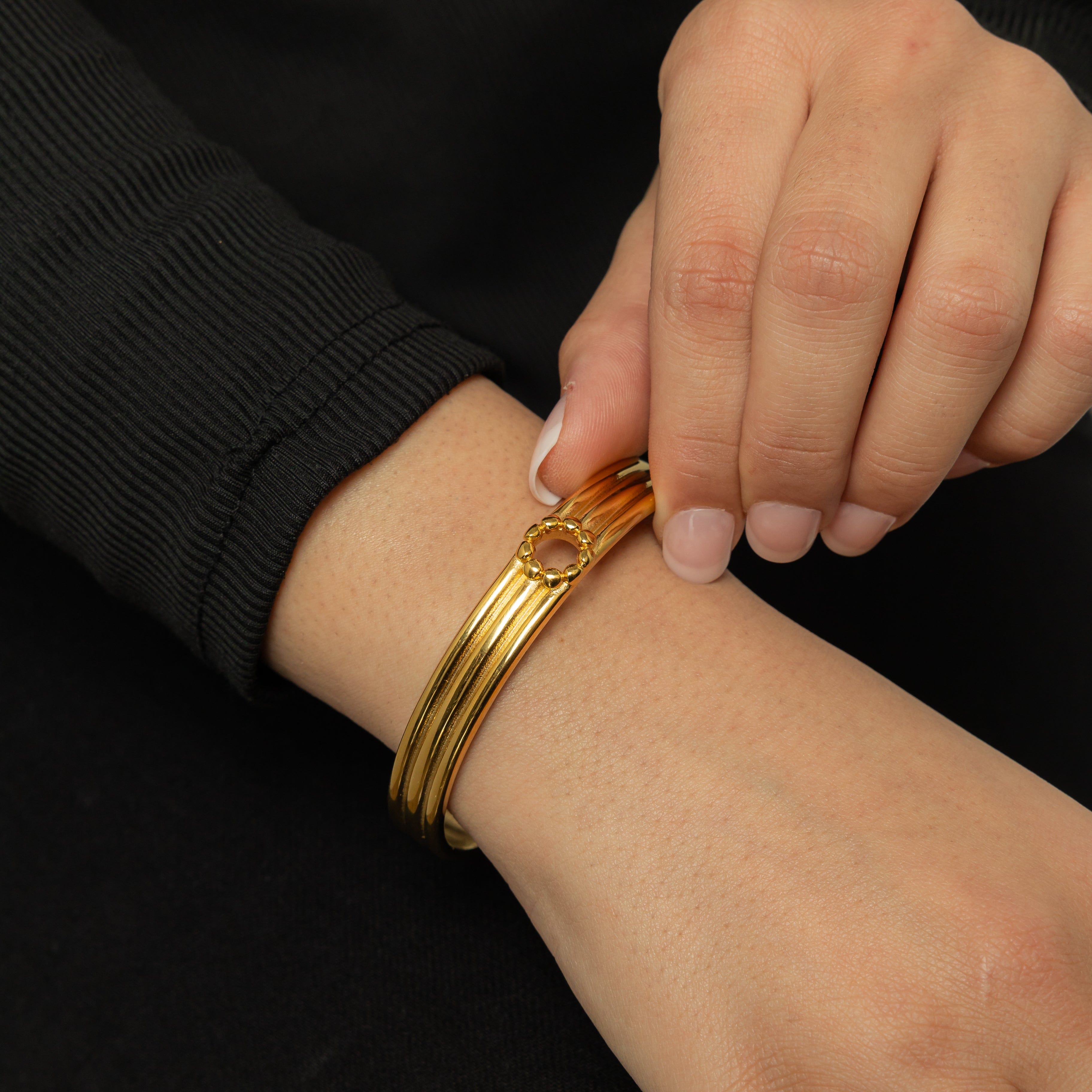 Elegant hand wearing the Eternal Blossom Bangle in a garden setting