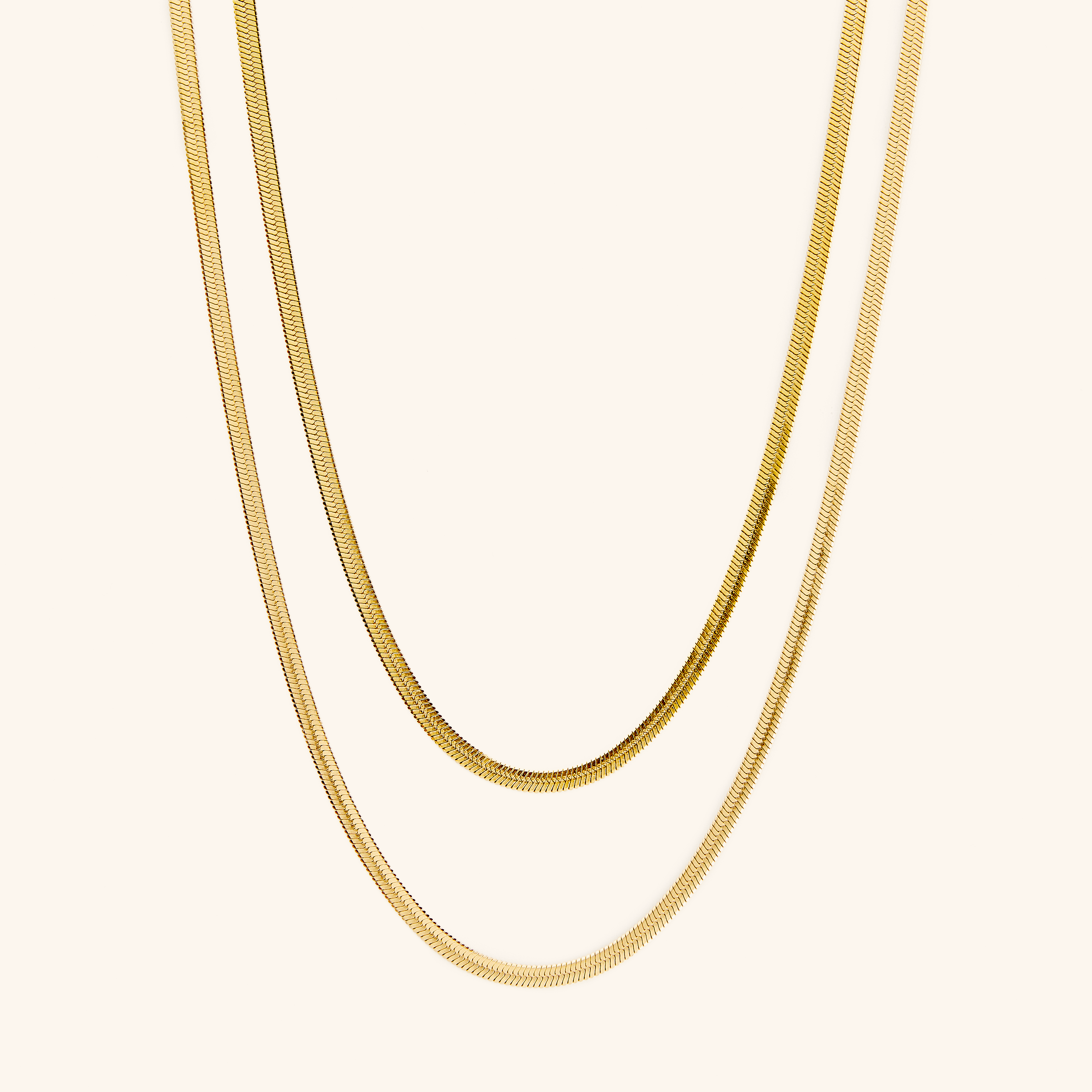 Close-up of the herringbone necklace showing interlocked gold-dipped links against skin