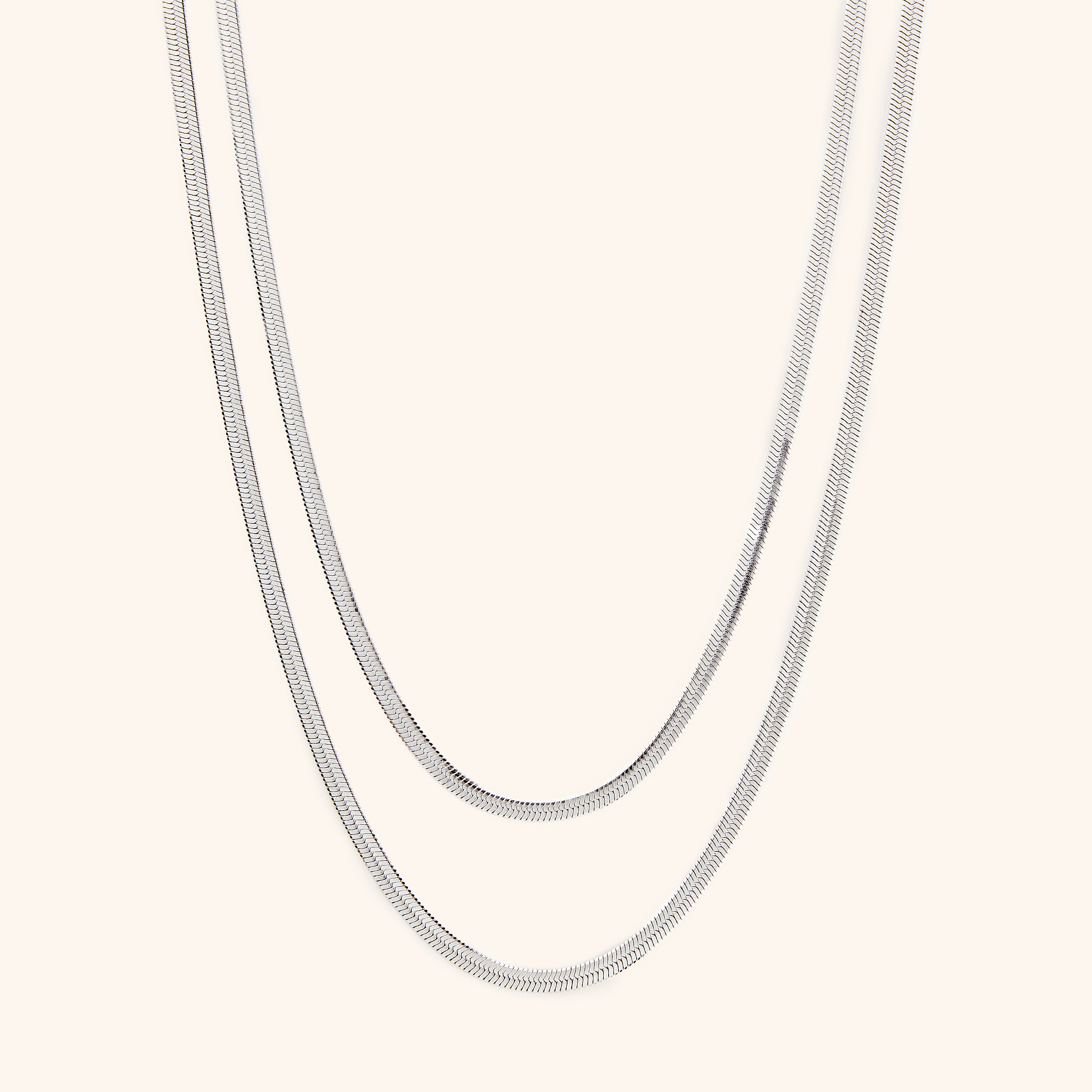 Close-up of the herringbone necklace showing interlocked gold-dipped links against skin