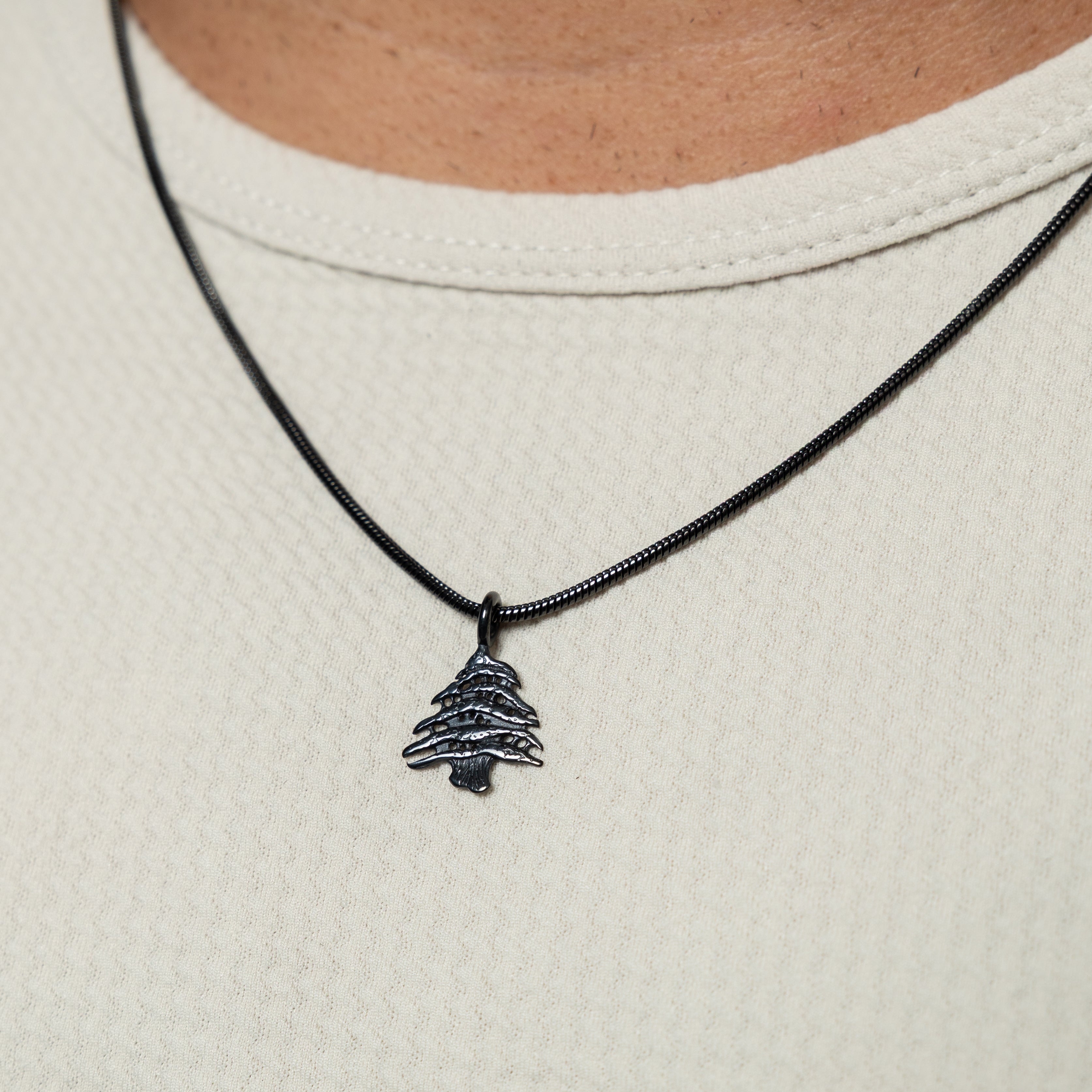 Cedar of Lebanon mens necklace hanging on display, showcasing its stainless steel shine and intricate design.