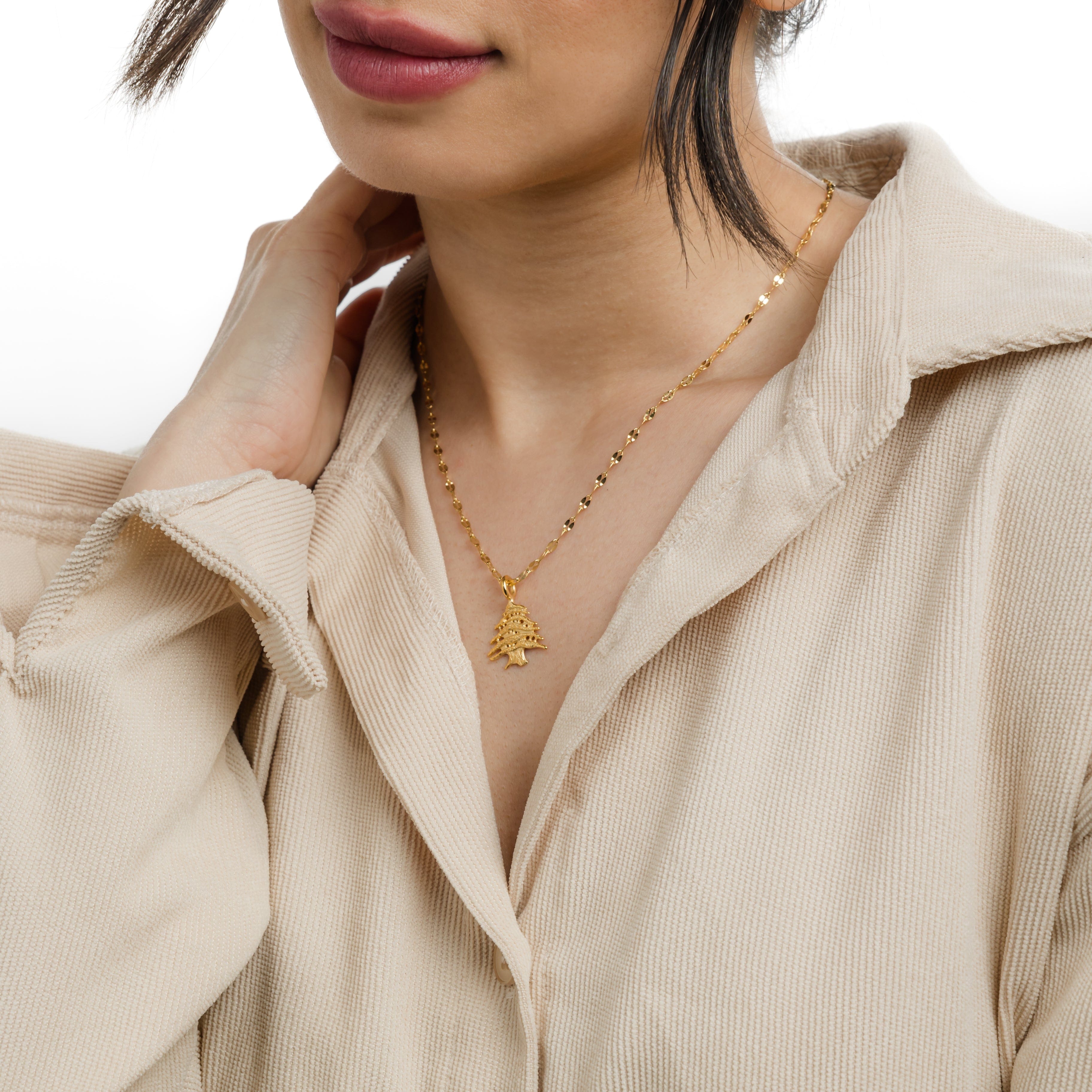 Cedar of Lebanon gold pendant necklace displayed on a velvet pouch.