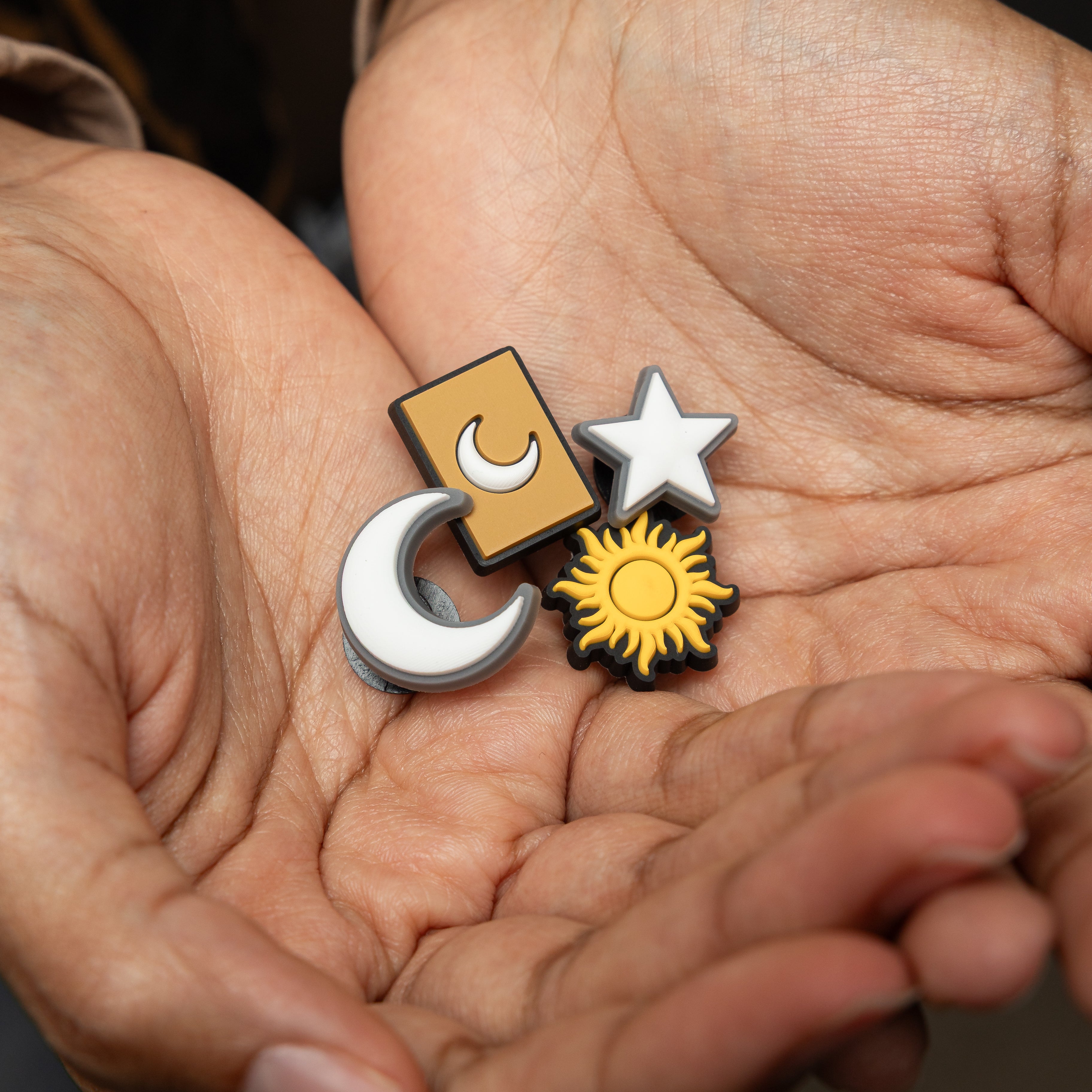 Close-up of the celestial charm pack for Crocs, showcasing the glowing crescent moon and radiant sun designs.