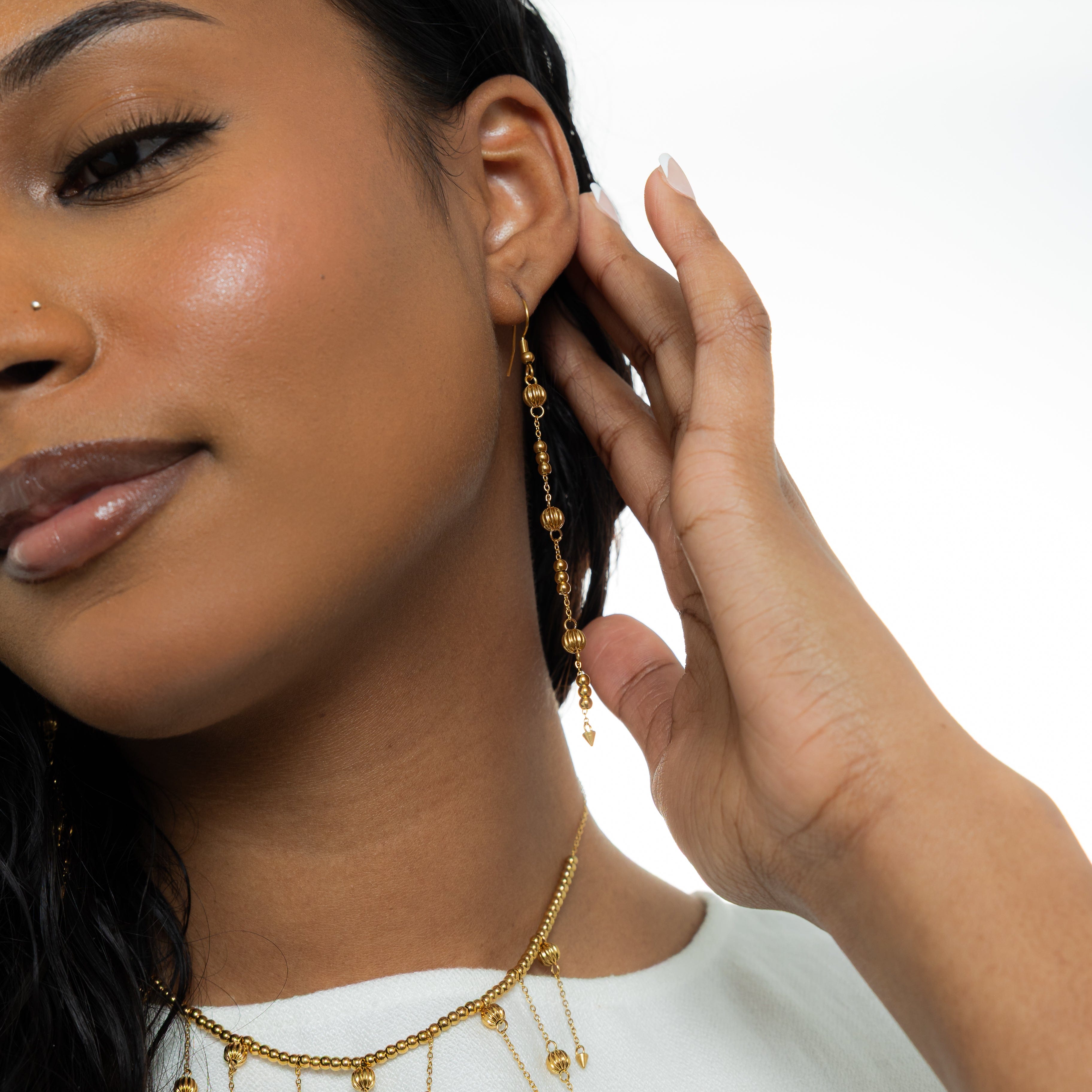 Close-up of gold dangle earrings highlighting their delicate orbs and craftsmanship.