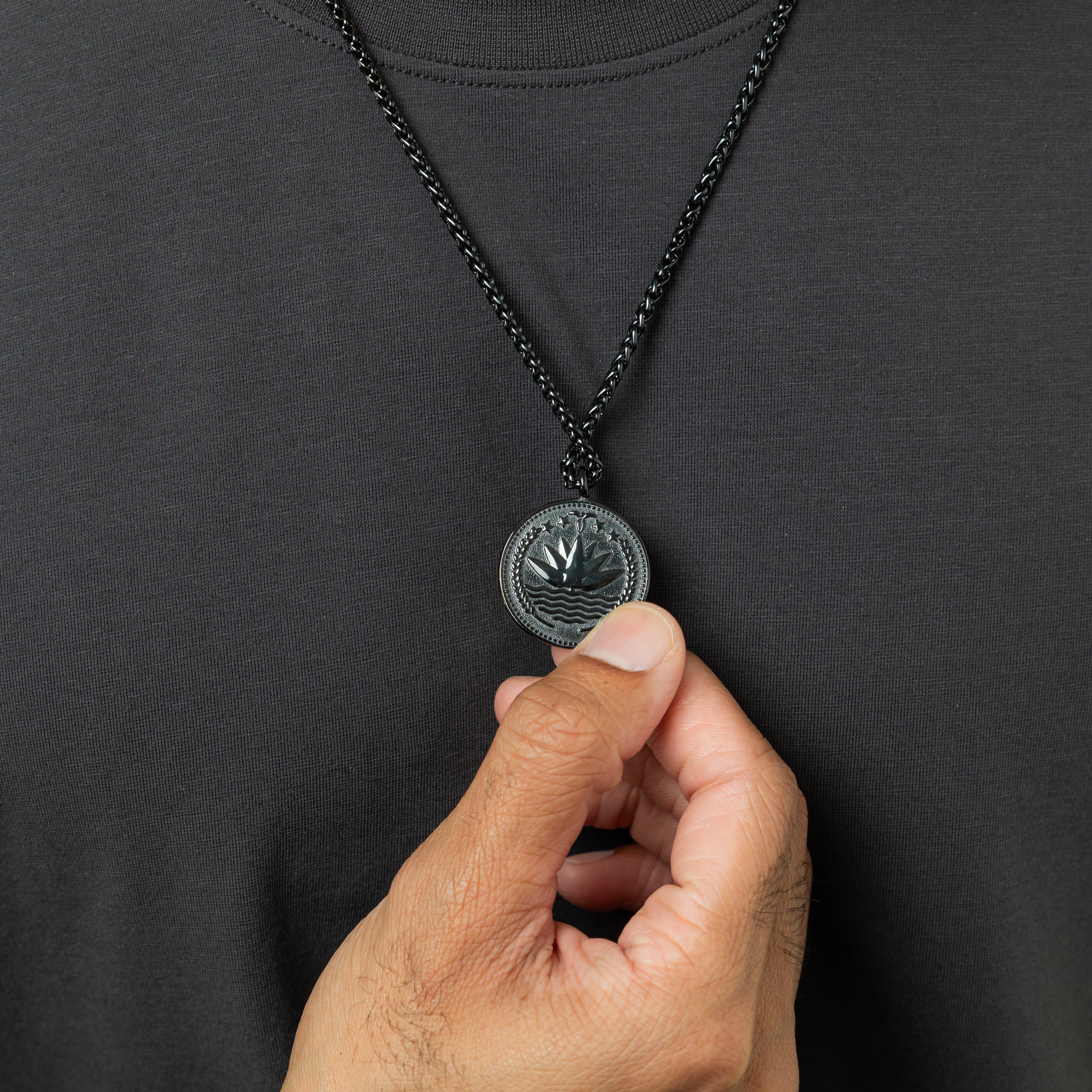 Close-up of the pendant on the mens necklace, showcasing the intricate country design against a soft surface.