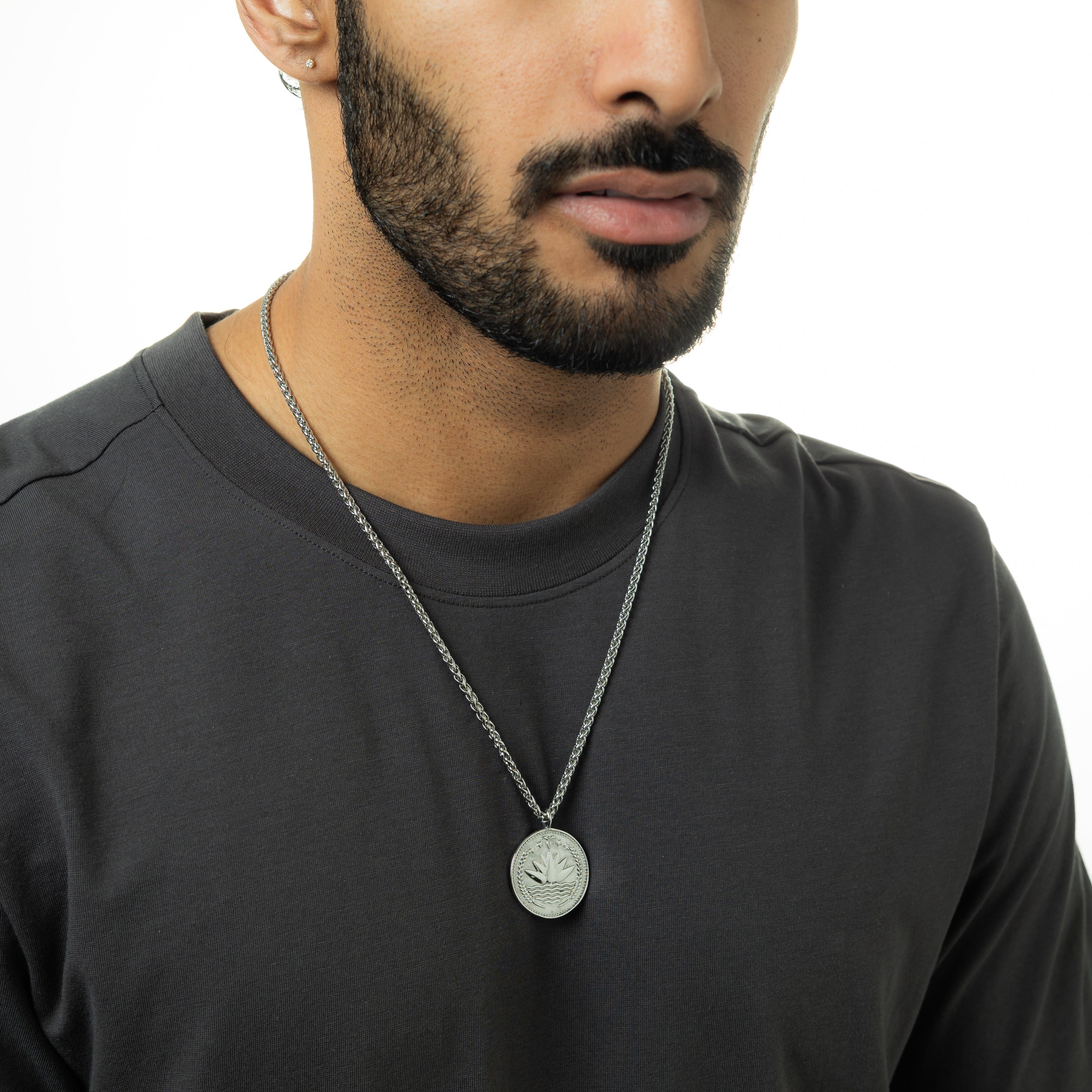 Close-up of the pendant on the mens necklace, showcasing the intricate country design against a soft surface.