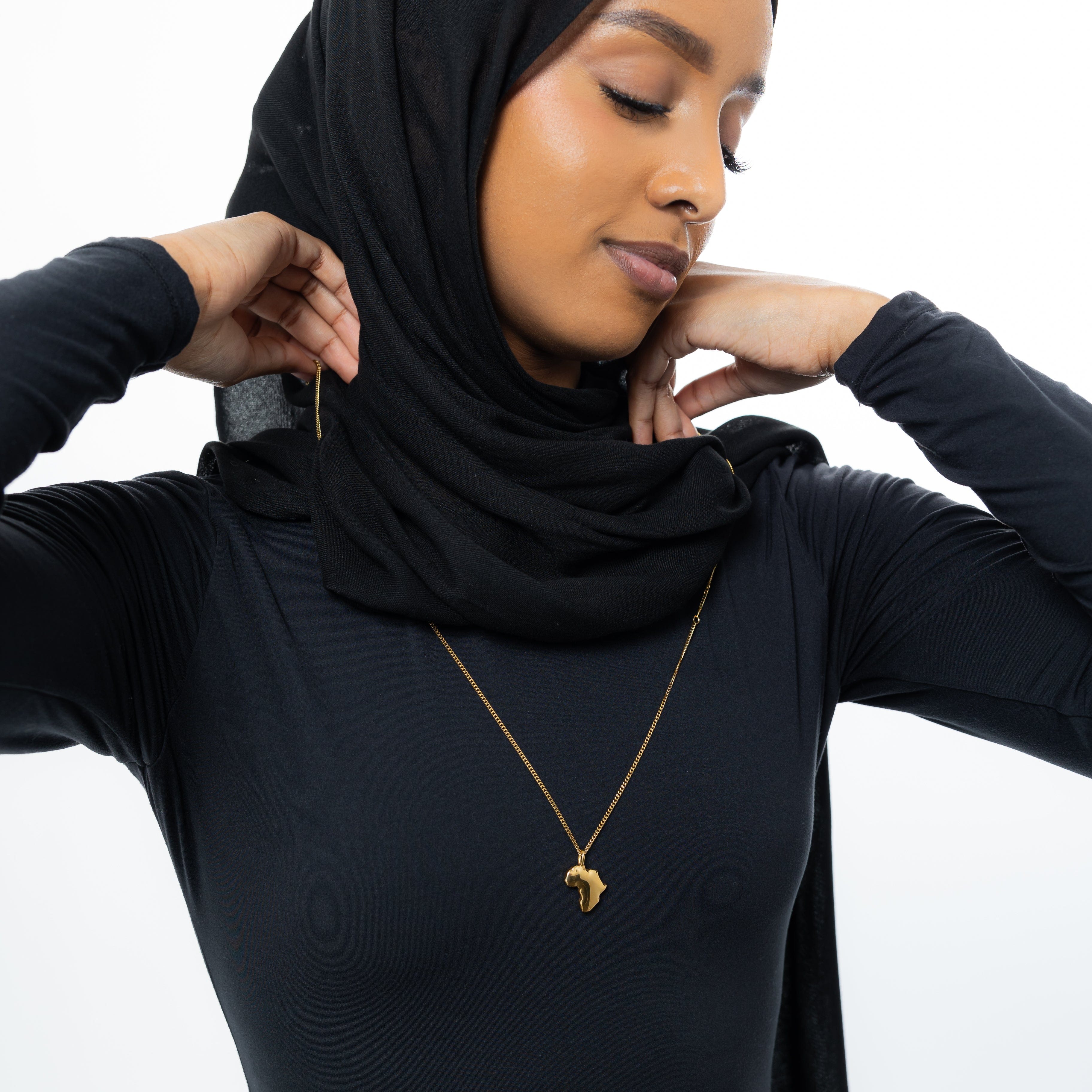 Close-up view of the affordable gold map charm on a carabiner necklace.