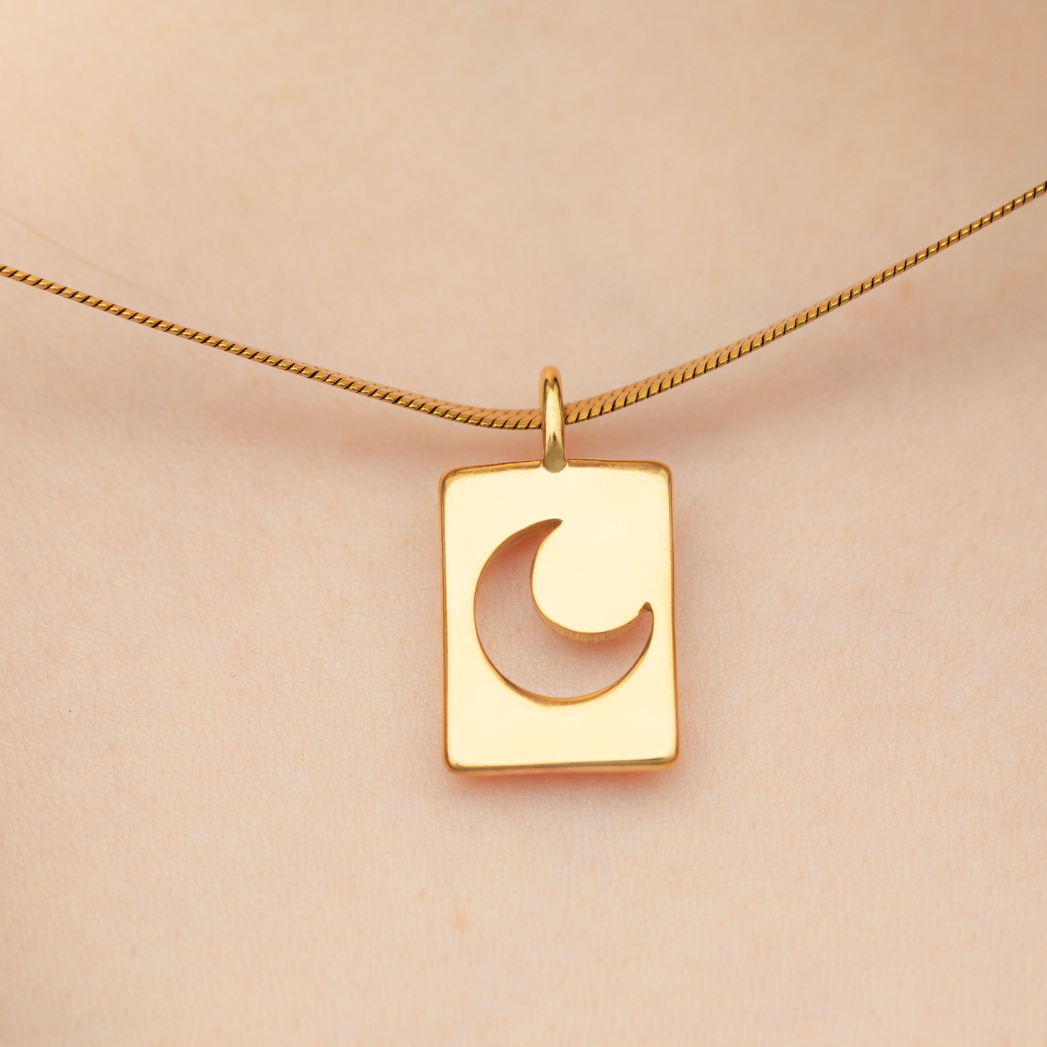Crescent moon charm elegantly layered on a necklace with other gold charms.