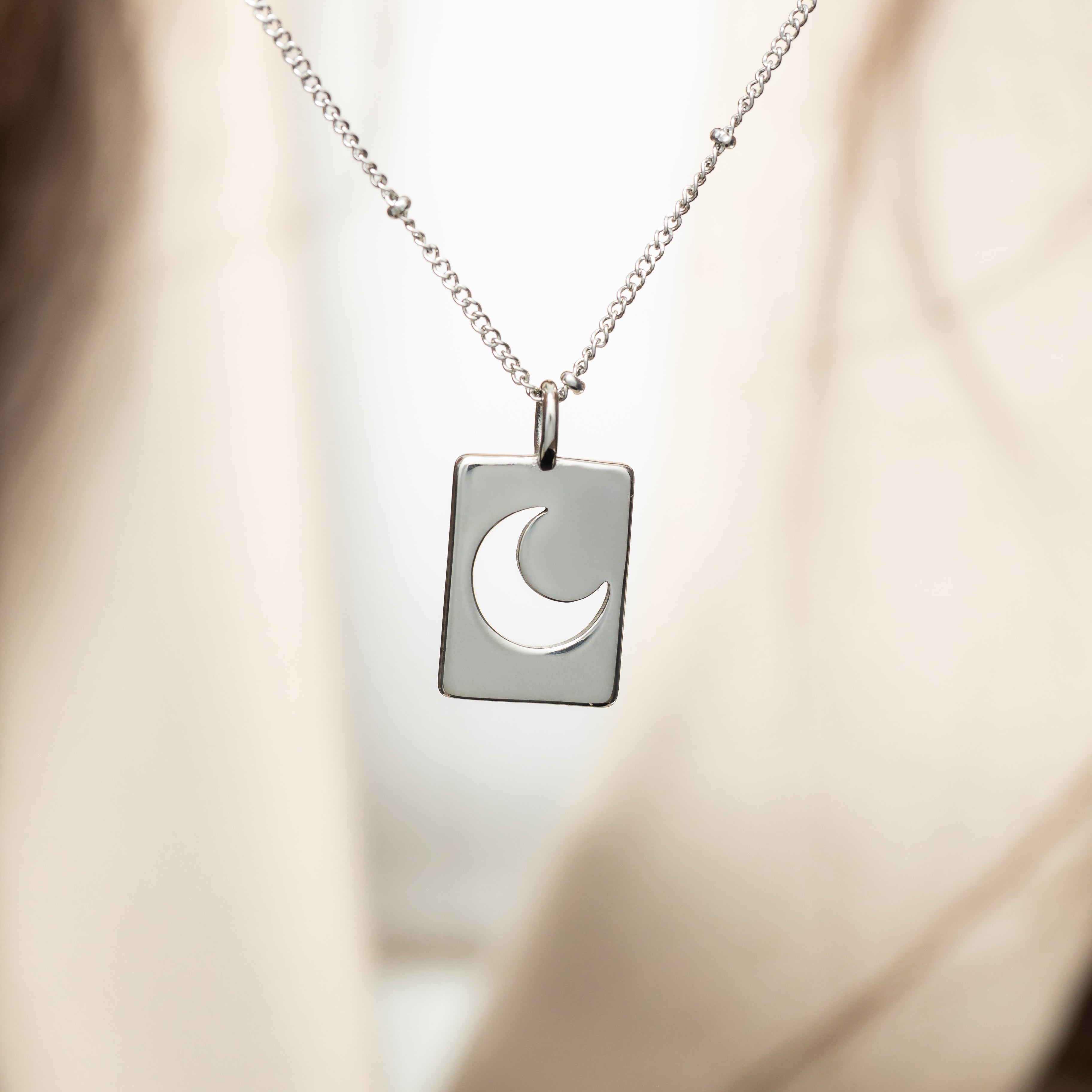 Crescent charm displayed in a velvet pouch, highlighting its hypoallergenic properties.
