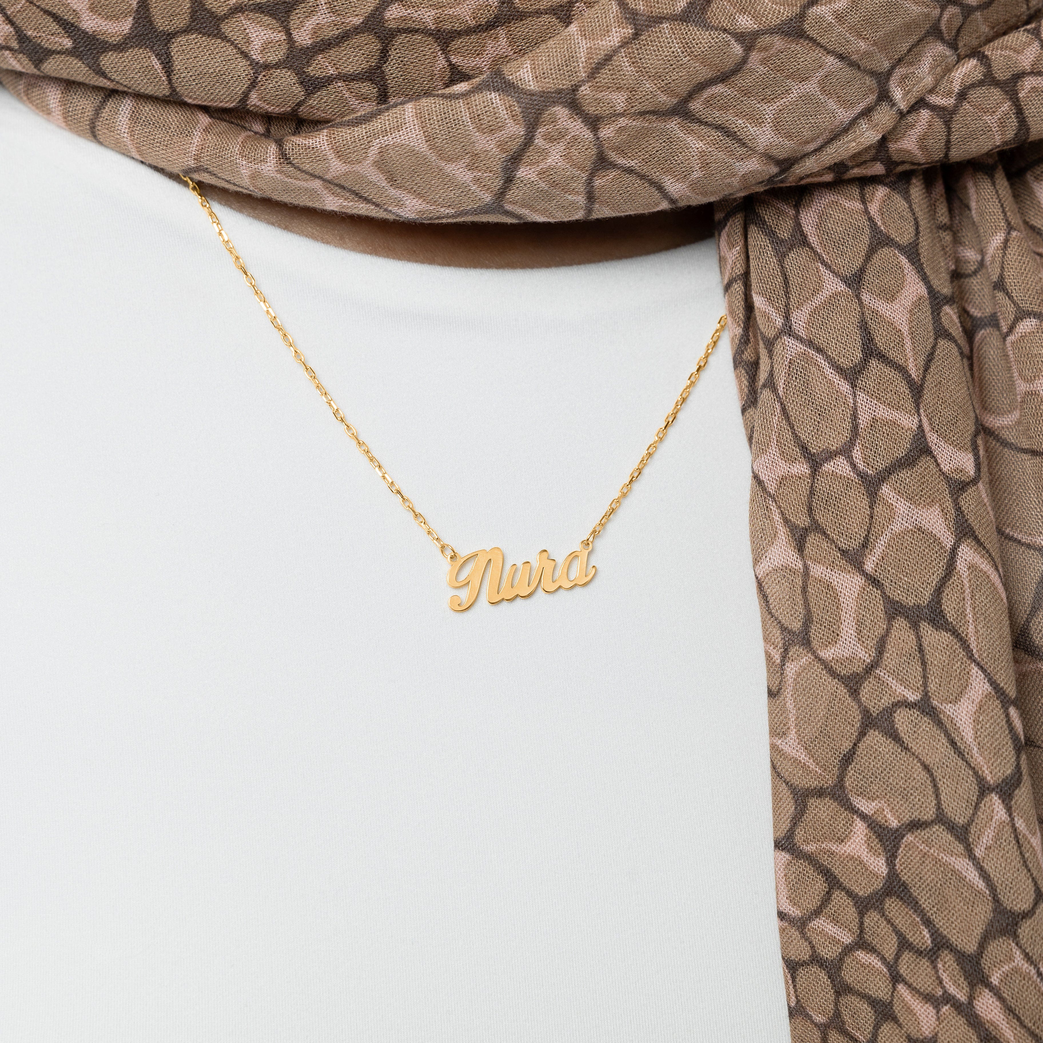 Model wearing a custom name necklace in a casual setting, emphasizing its versatility and style.