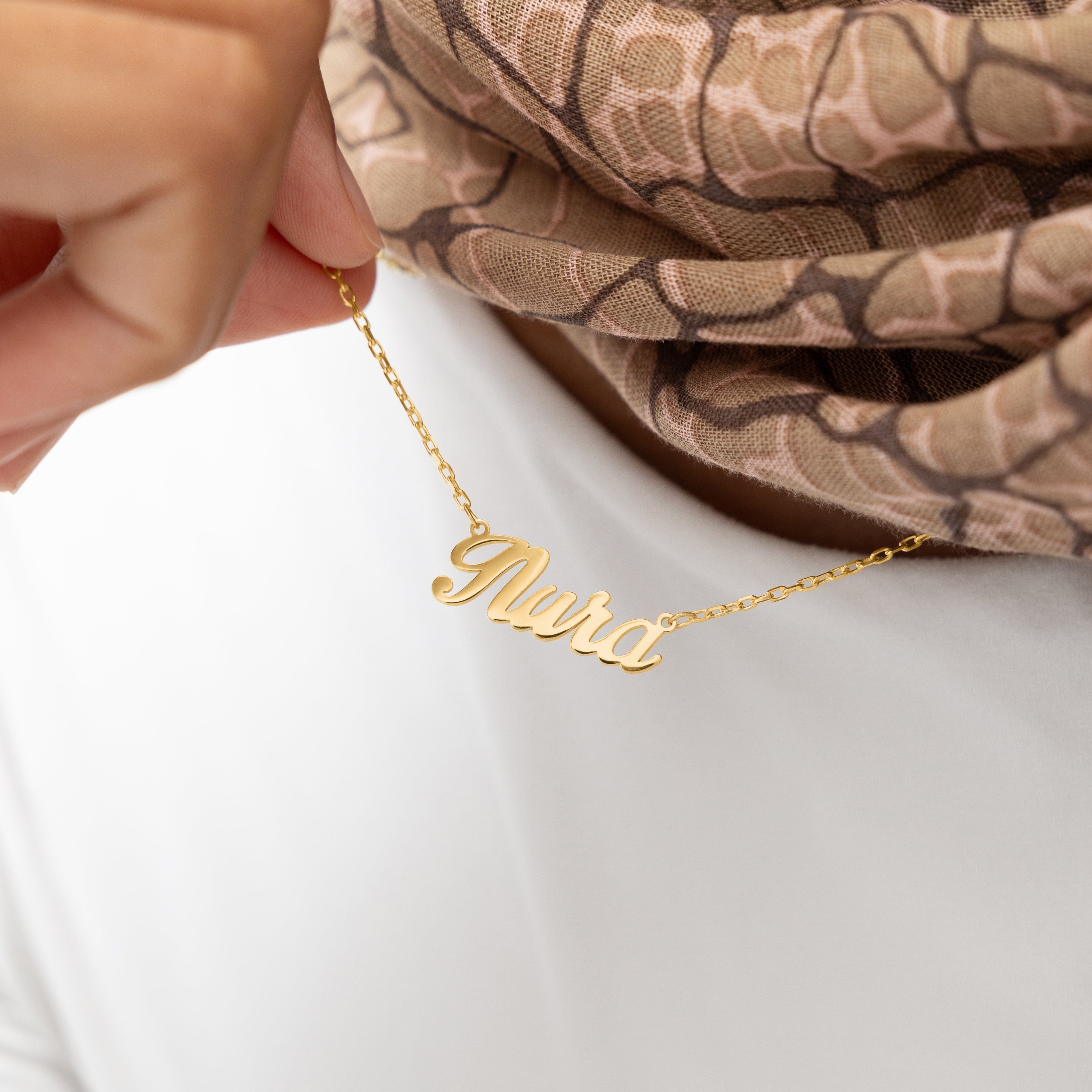 Model wearing a custom name necklace in a casual setting, emphasizing its versatility and style.