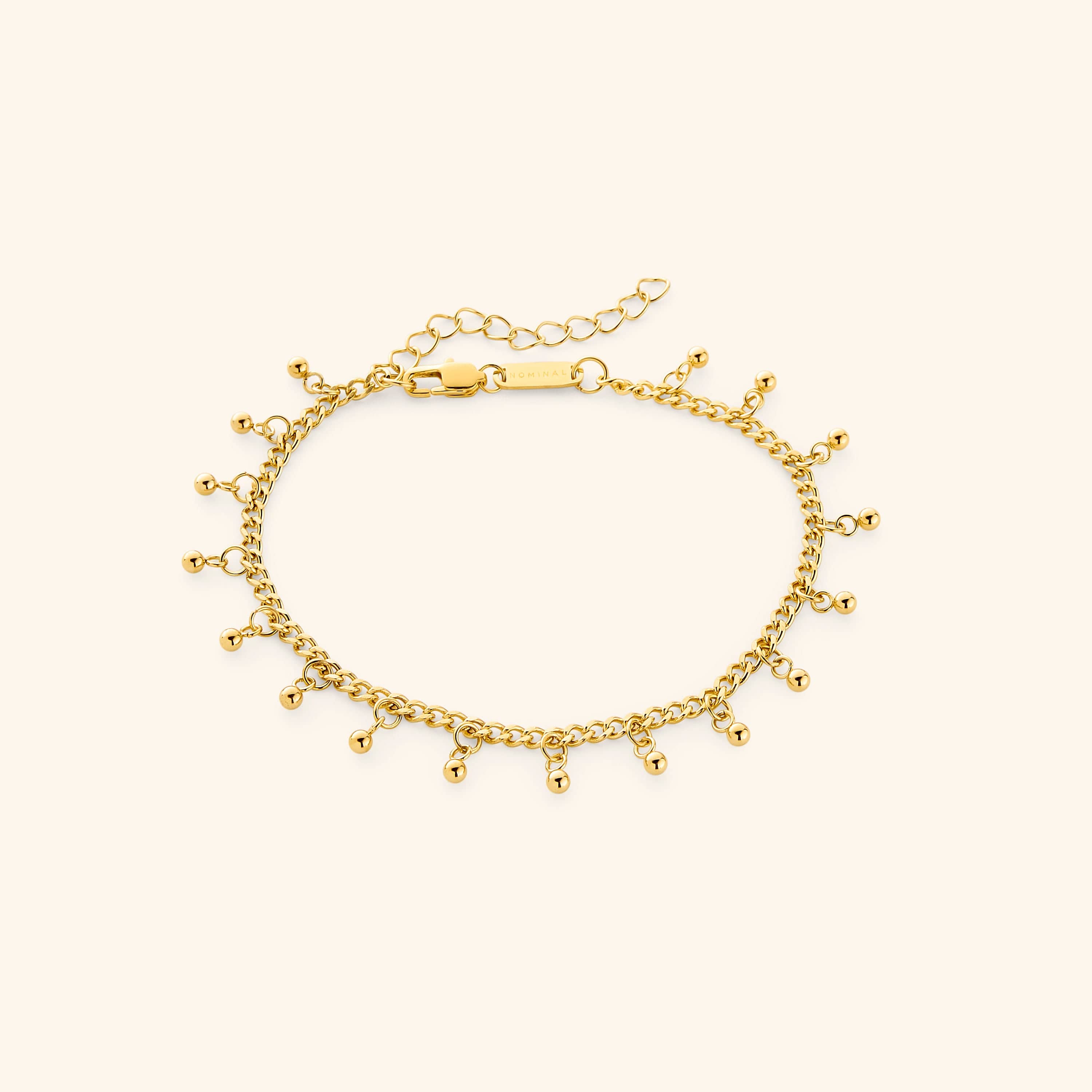 Close-up view of the elegant gold dotted anklet on a model's ankle, showcasing its delicate charms.
