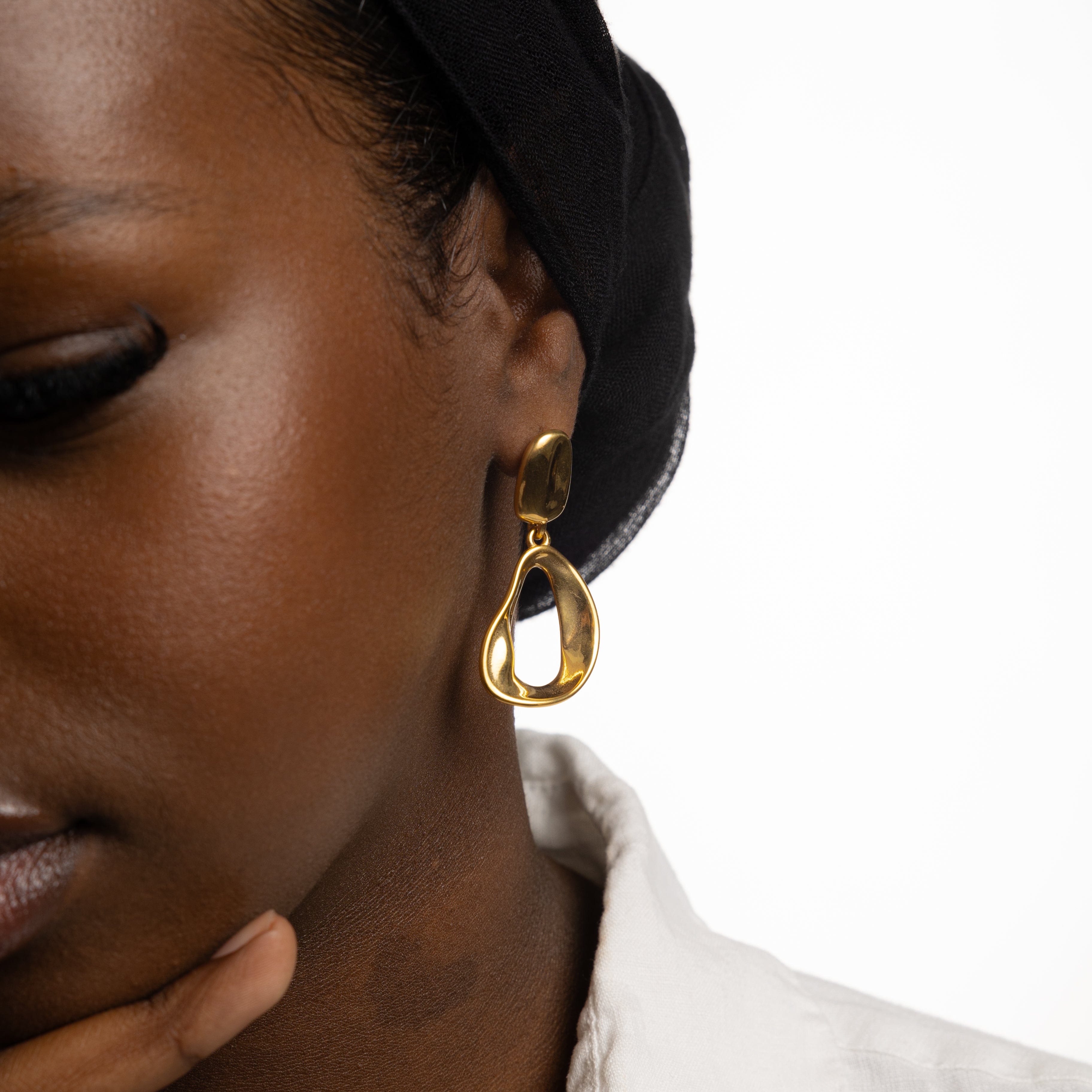 Close-up of Fluid Elegance Gold Statement Earrings highlighting the melting stud and oval hoop design.