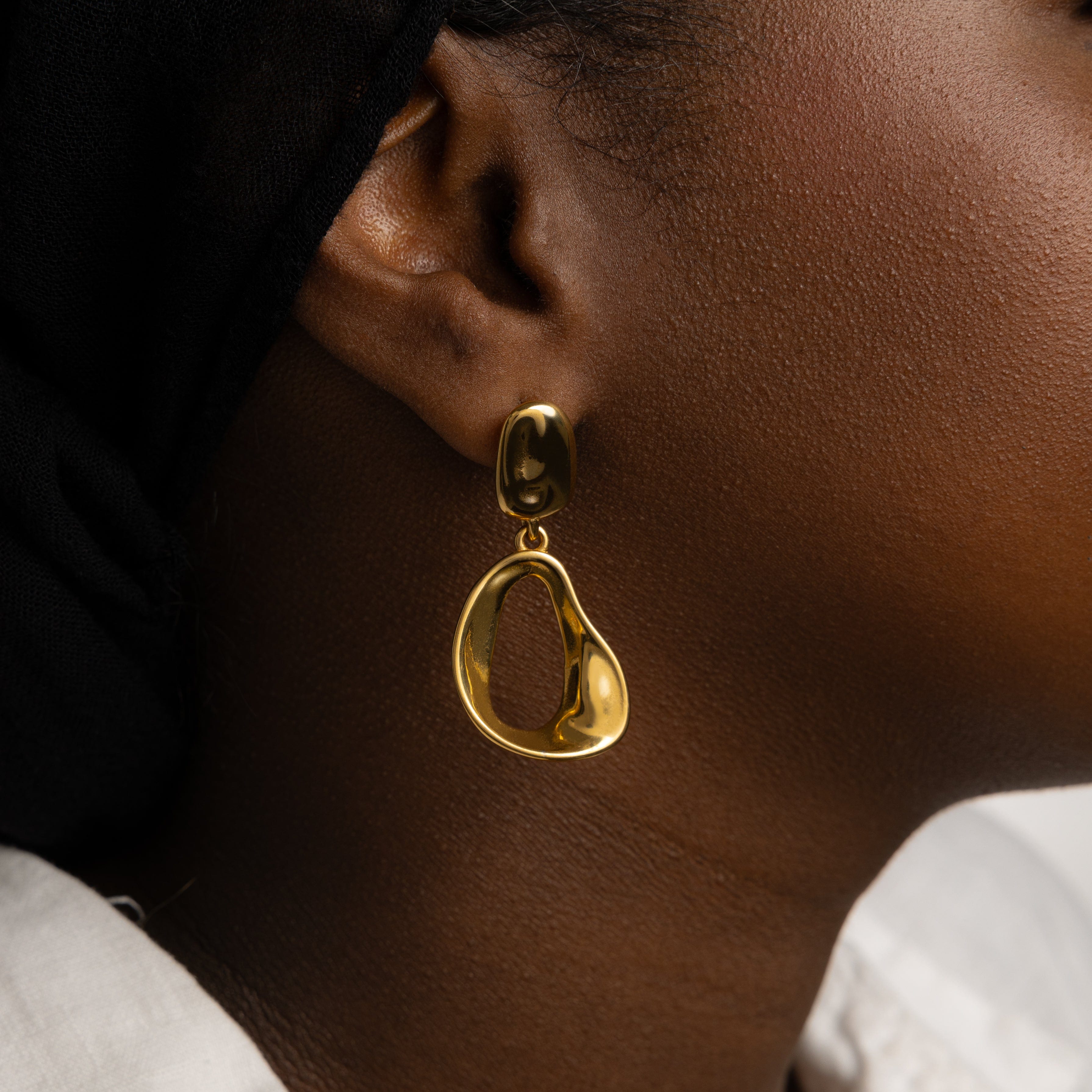 Model wearing Fluid Elegance Gold Statement Earrings at a casual outing, demonstrating their versatility.