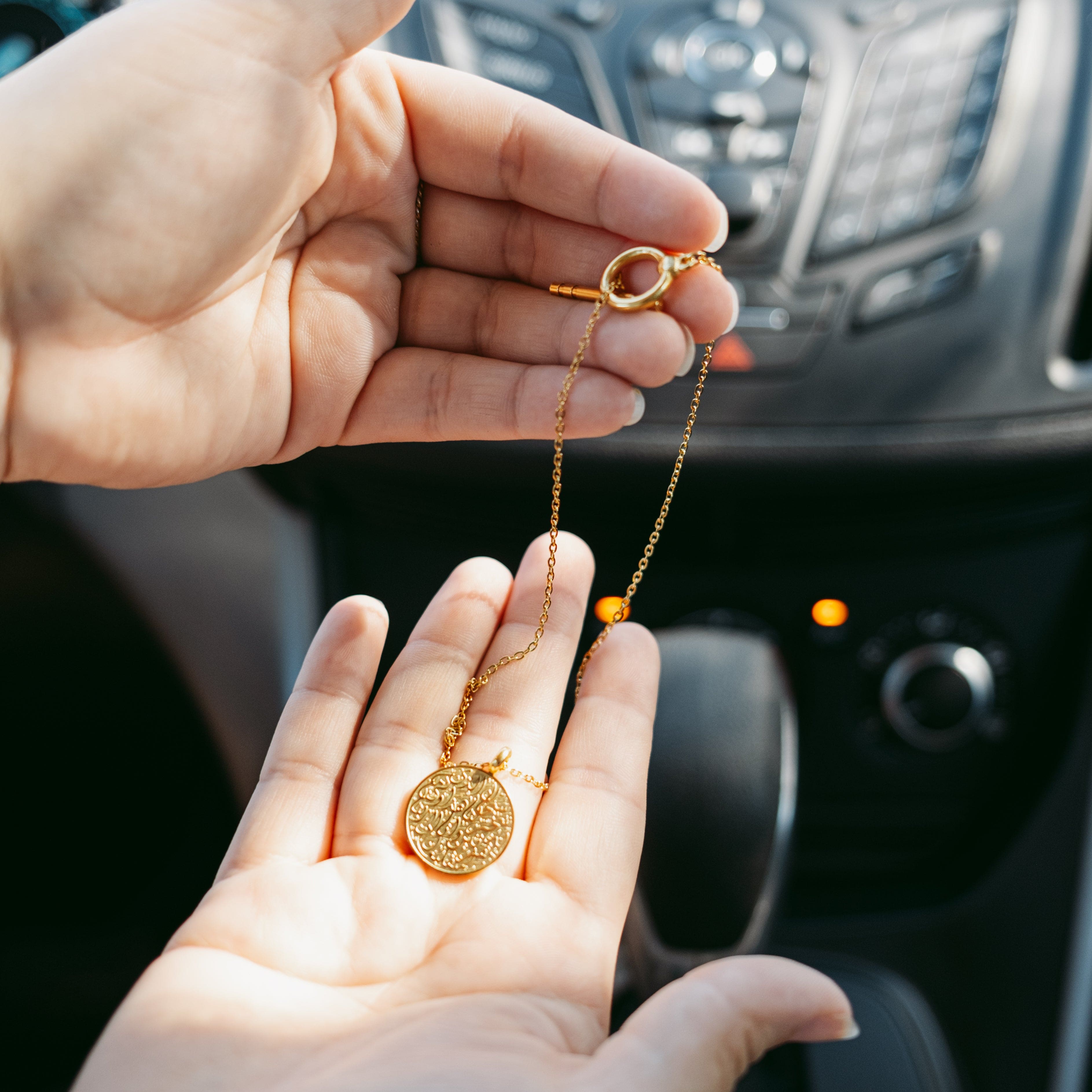 Elegant 18K Gold Travel Prayer Car Hanger displayed on a car dashboard, showcasing its beautiful engraving.