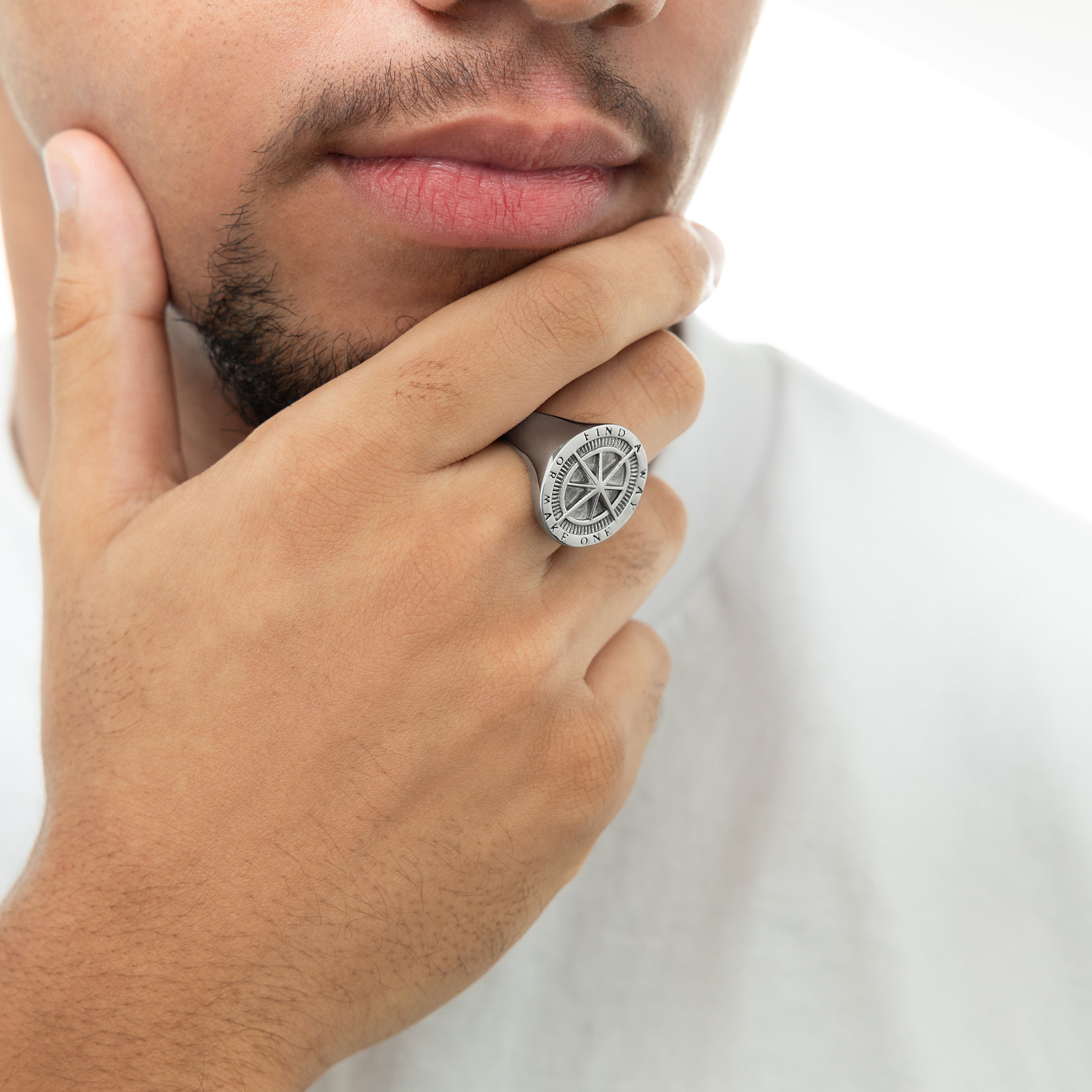 Close-up of the stainless steel compass ring against a natural backdrop, highlighting its craftsmanship.