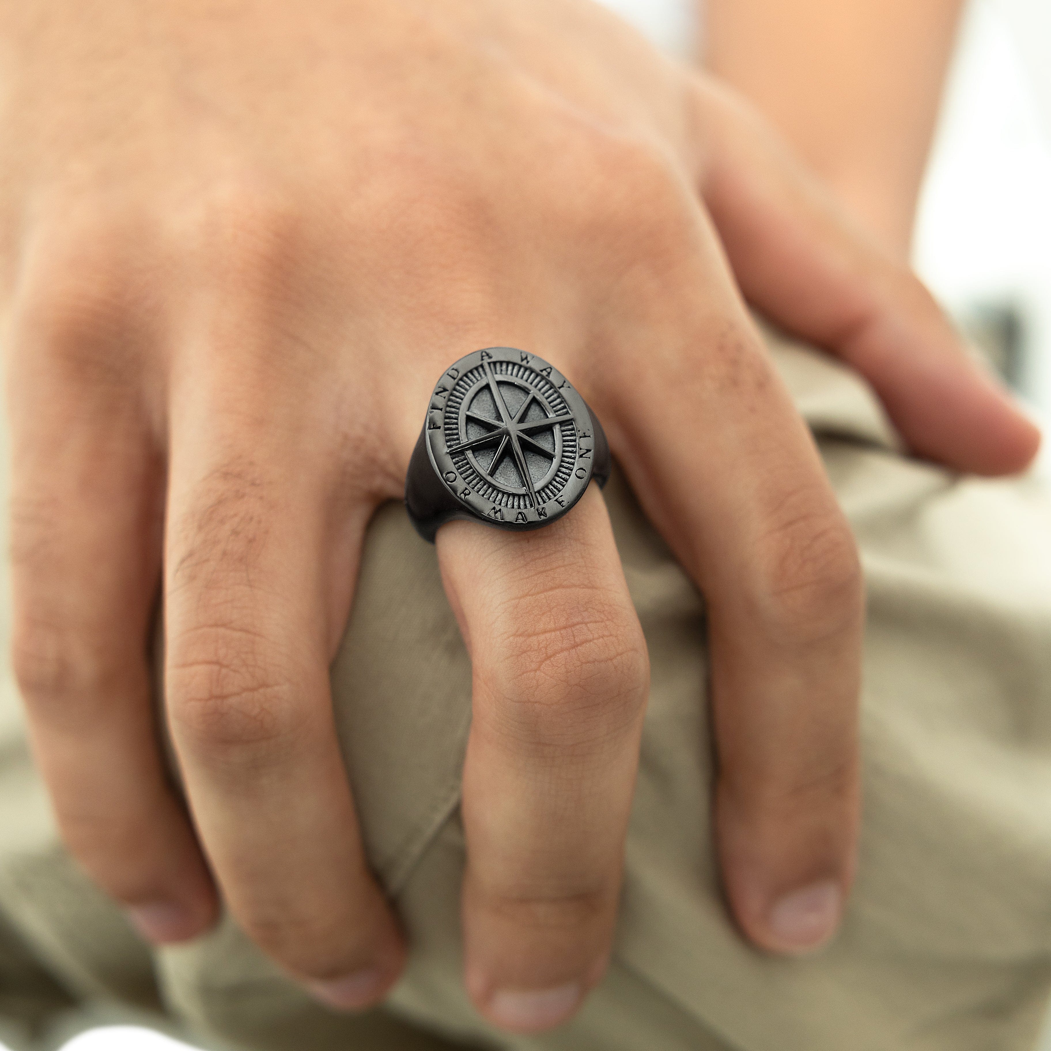 Close-up of the stainless steel compass ring against a natural backdrop, highlighting its craftsmanship.