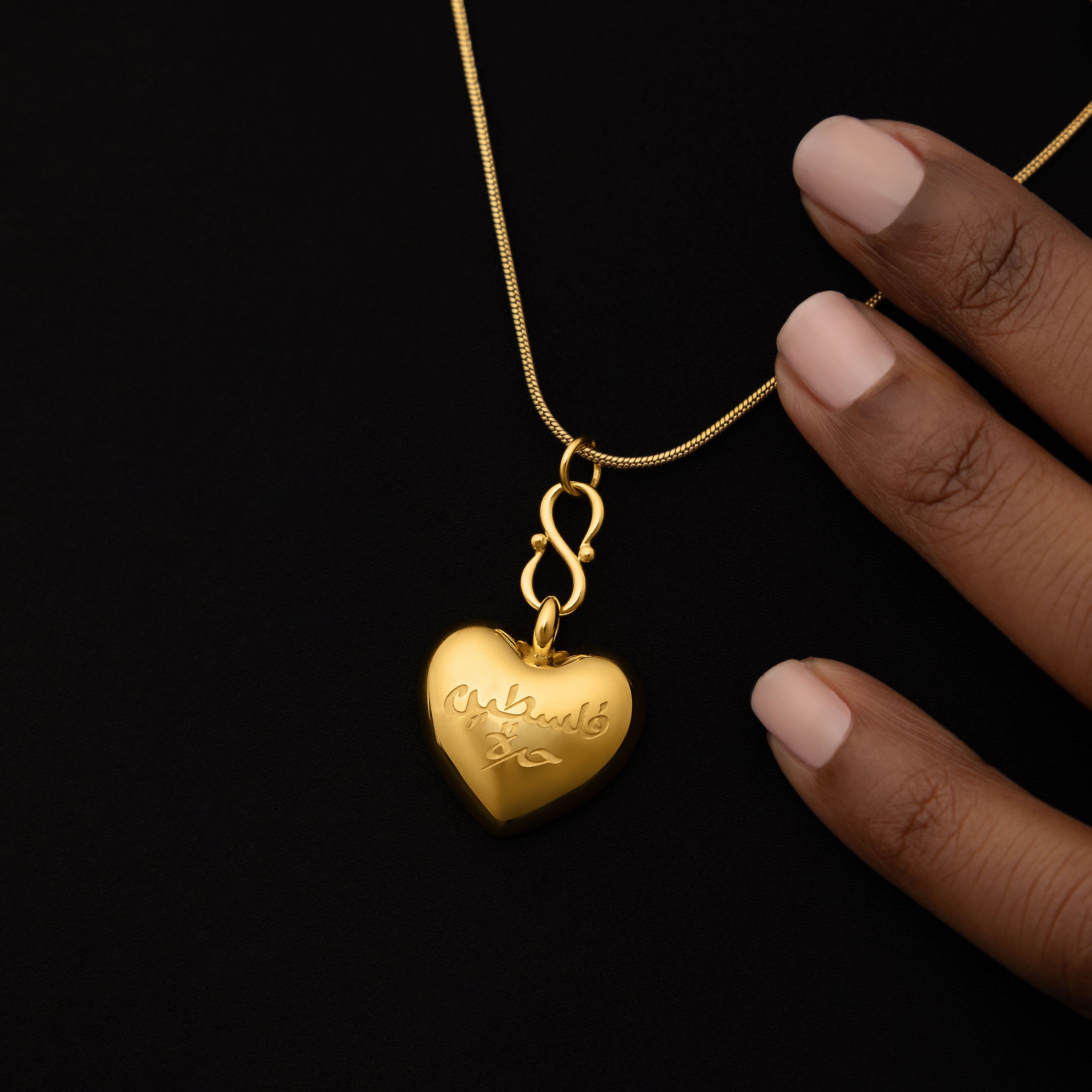 Close-up of the Free Palestine heart pendant, highlighting the engraved Arabic text.