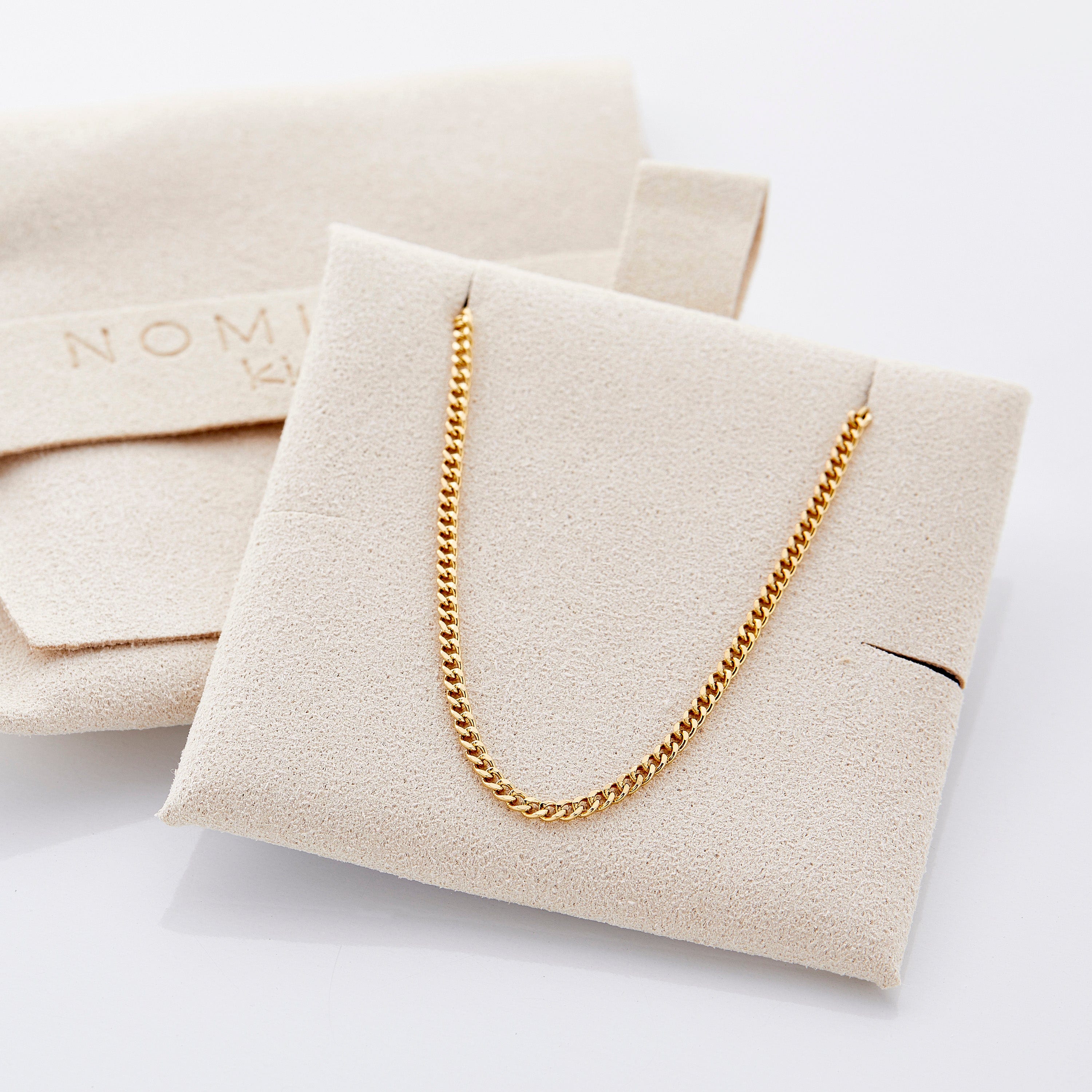 Elegant presentation of the gold necklace in a velvet drawstring pouch.