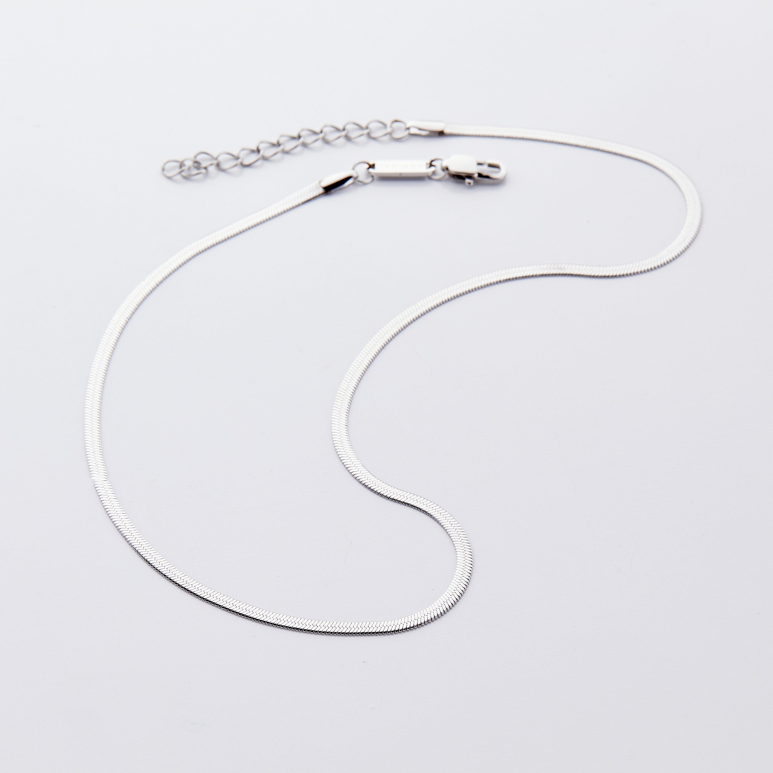 Flat lay of the Liquid Gold Herringbone Necklace in a velvet pouch, emphasizing its luxurious packaging.