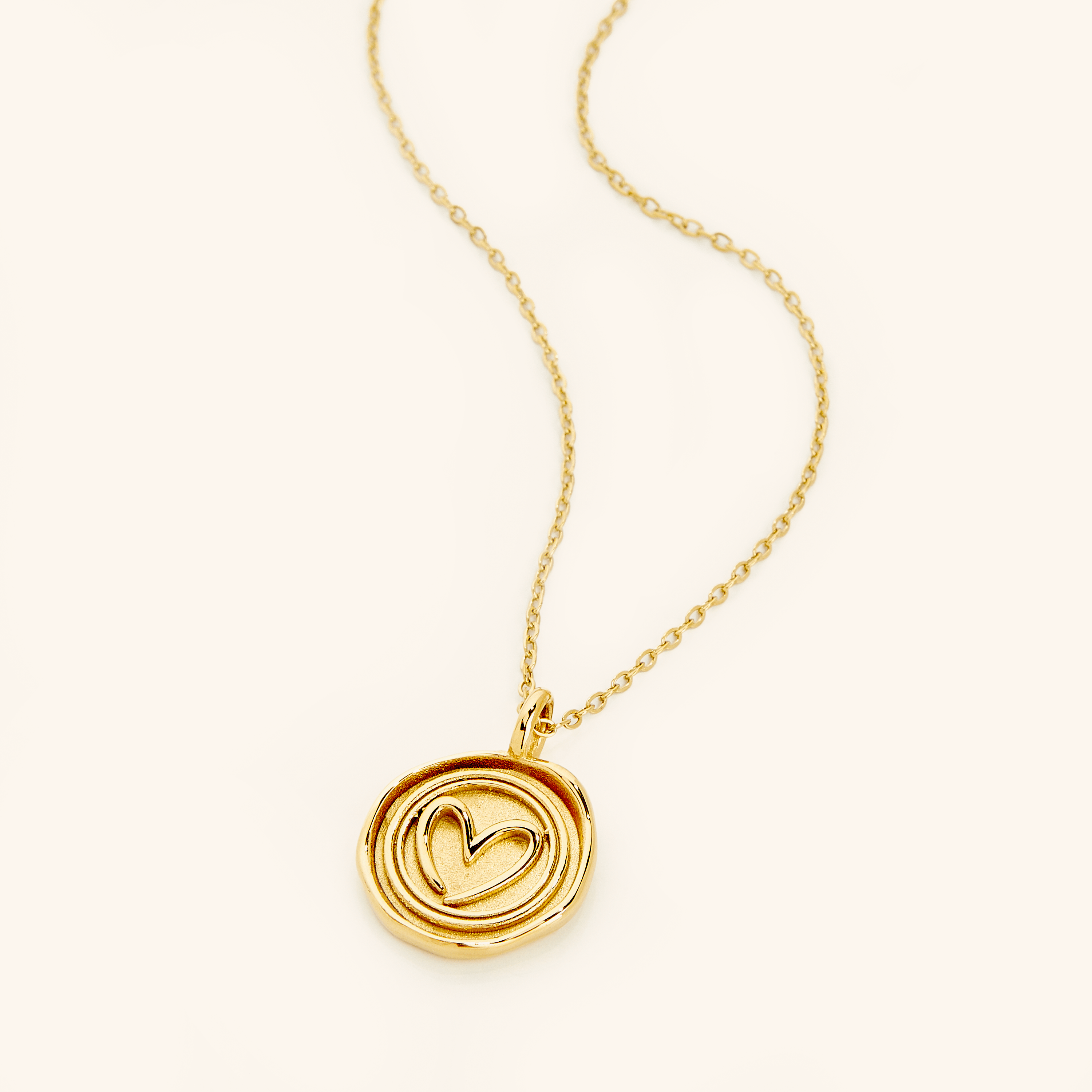 Heart stamp necklace showing unique swirling design and golden shine.