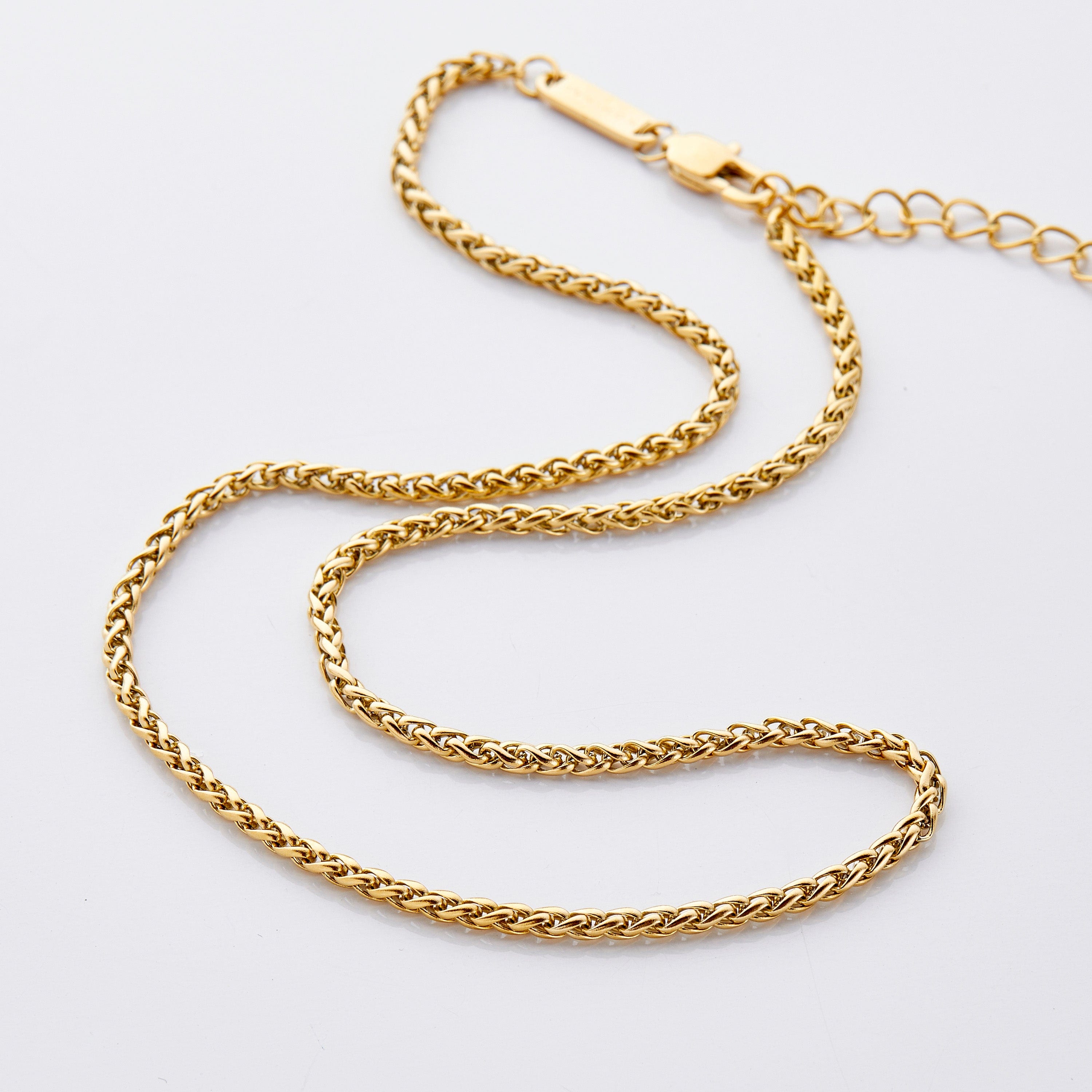 Gold wheat chain necklace for girls displayed on a velvet pouch.