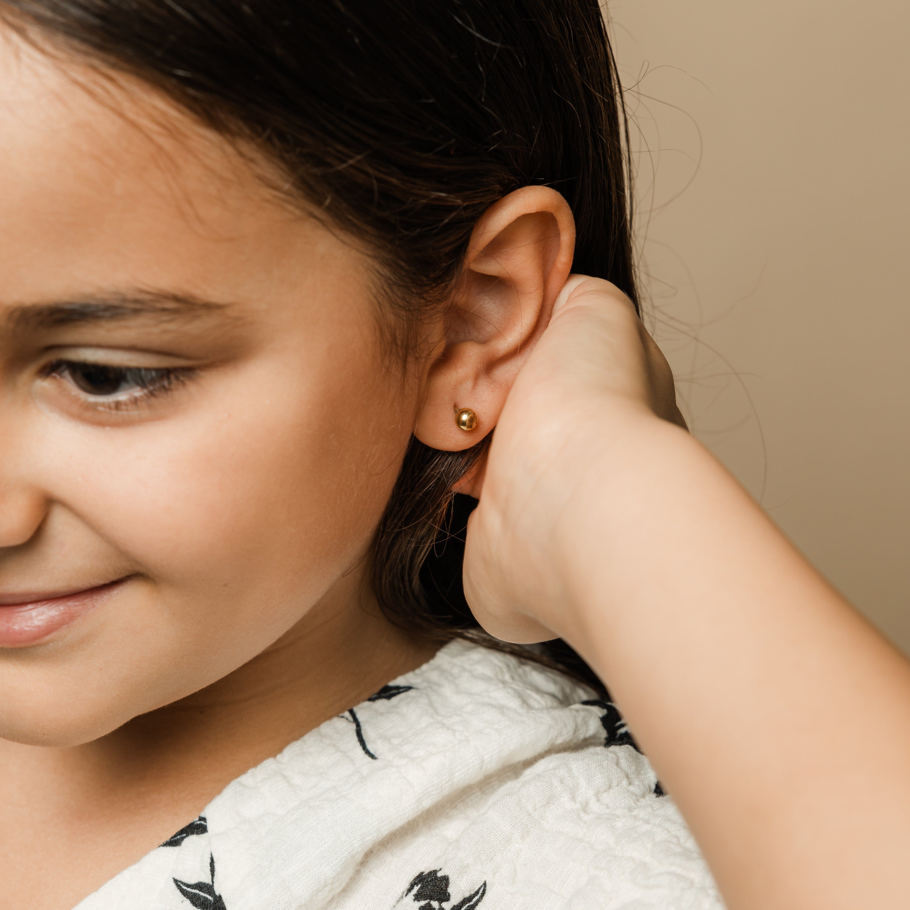 Timeless Gold Orb Earrings worn by a young girl, demonstrating their hypoallergenic properties.