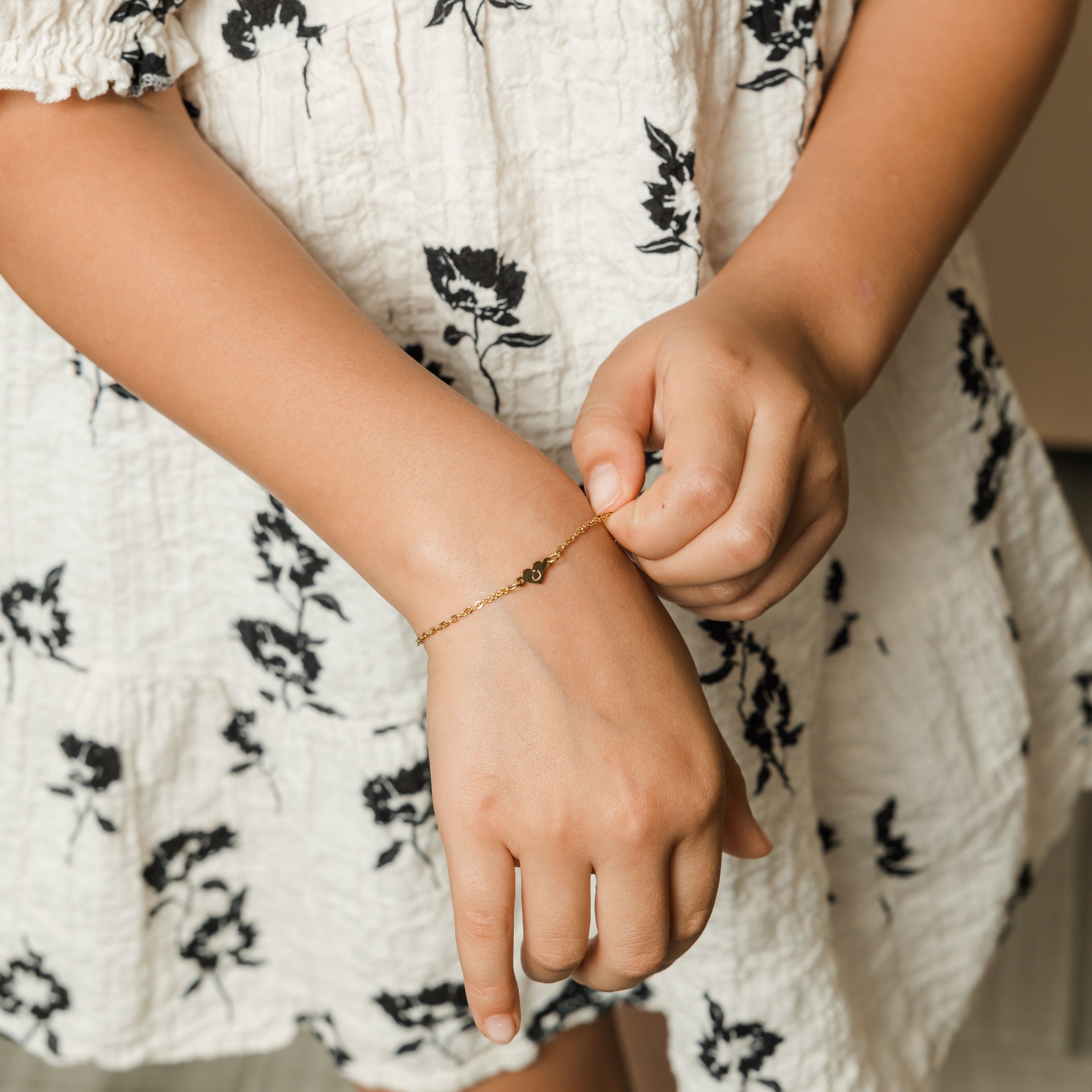 Personalized heart name bracelet for kids with letter pendant displayed elegantly.