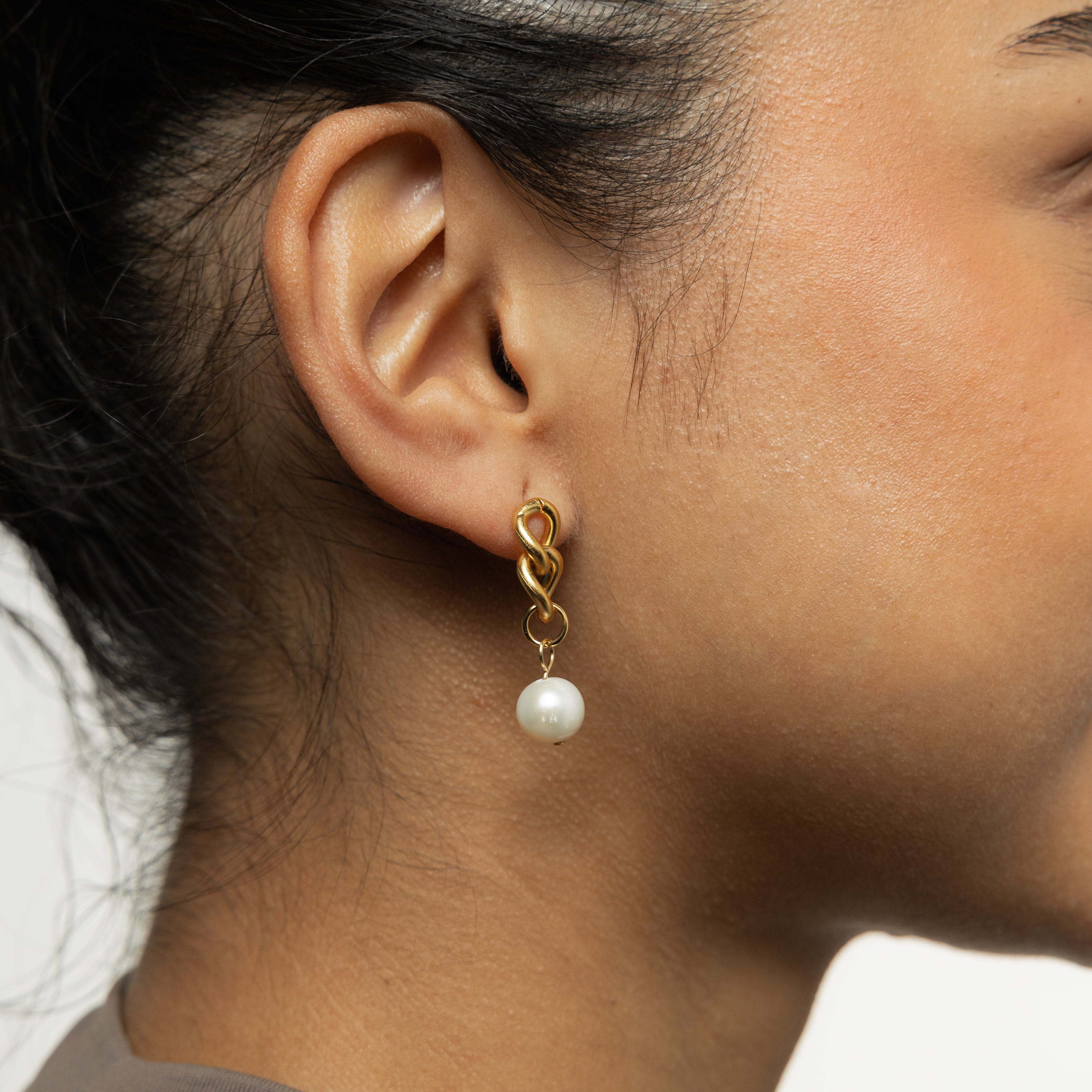Close-up of the hanging pearl earrings highlighting the detail of the freshwater pearls and cuban links.