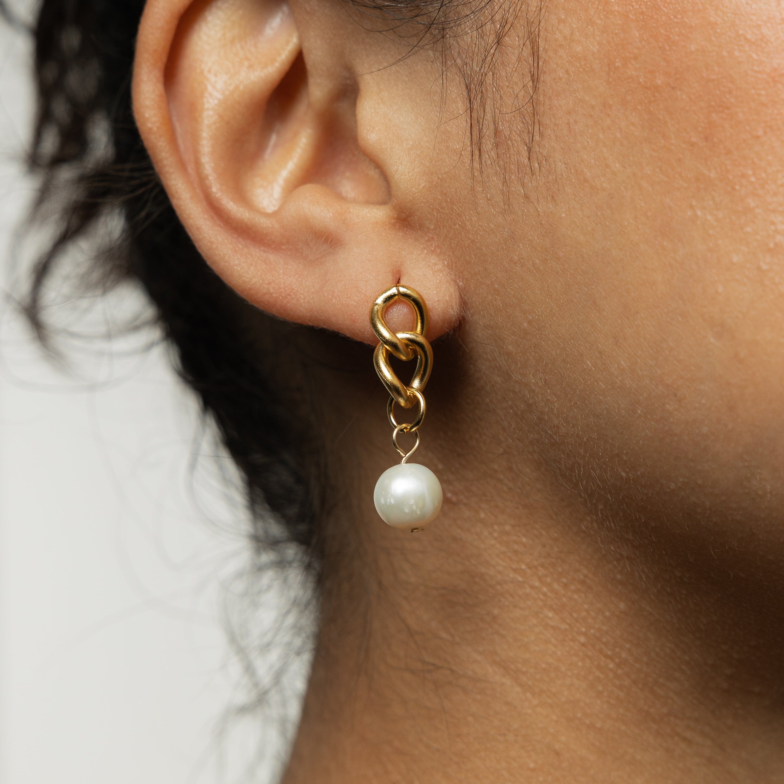 Close-up of the hanging pearl earrings highlighting the detail of the freshwater pearls and cuban links.