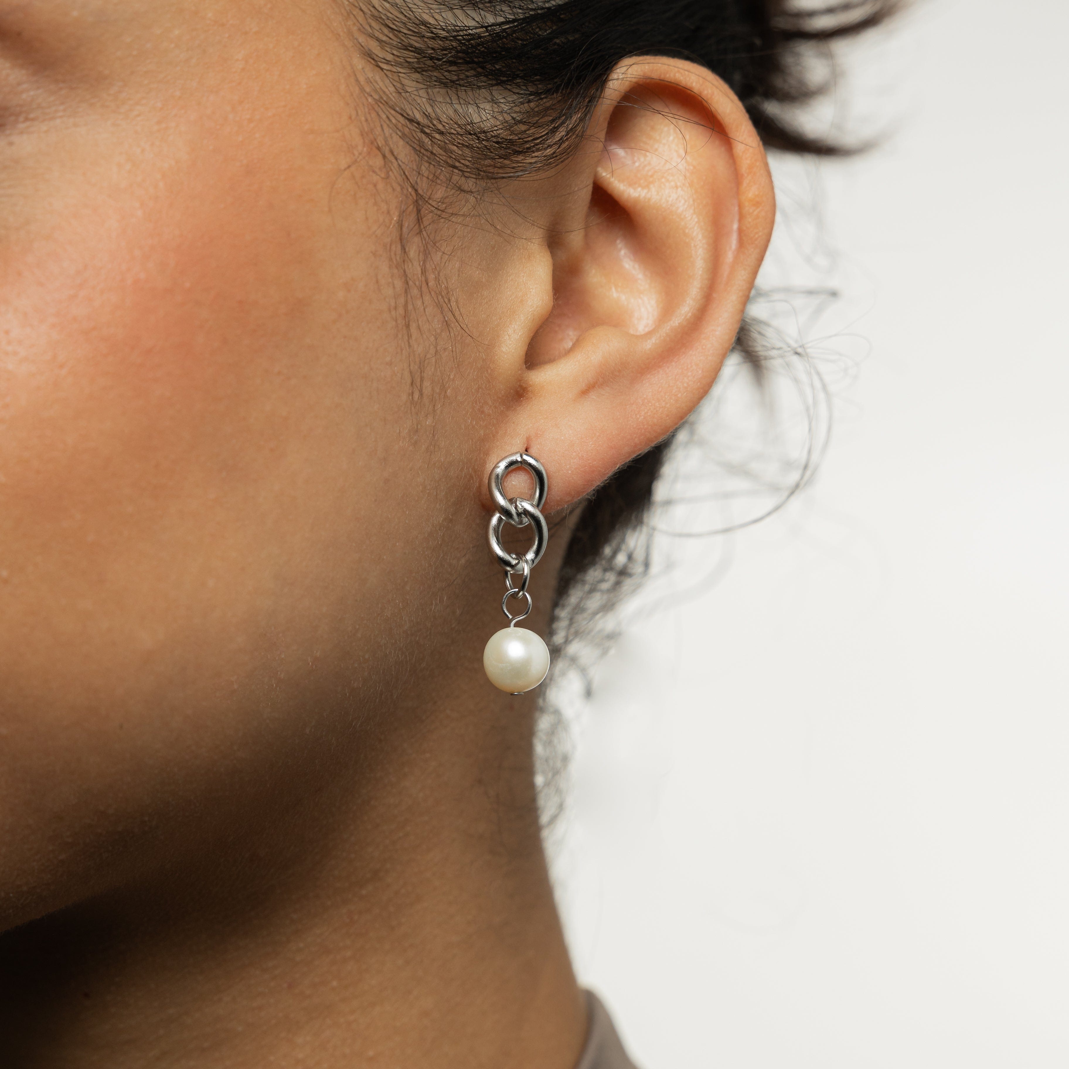 Close-up of the hanging pearl earrings highlighting the detail of the freshwater pearls and cuban links.