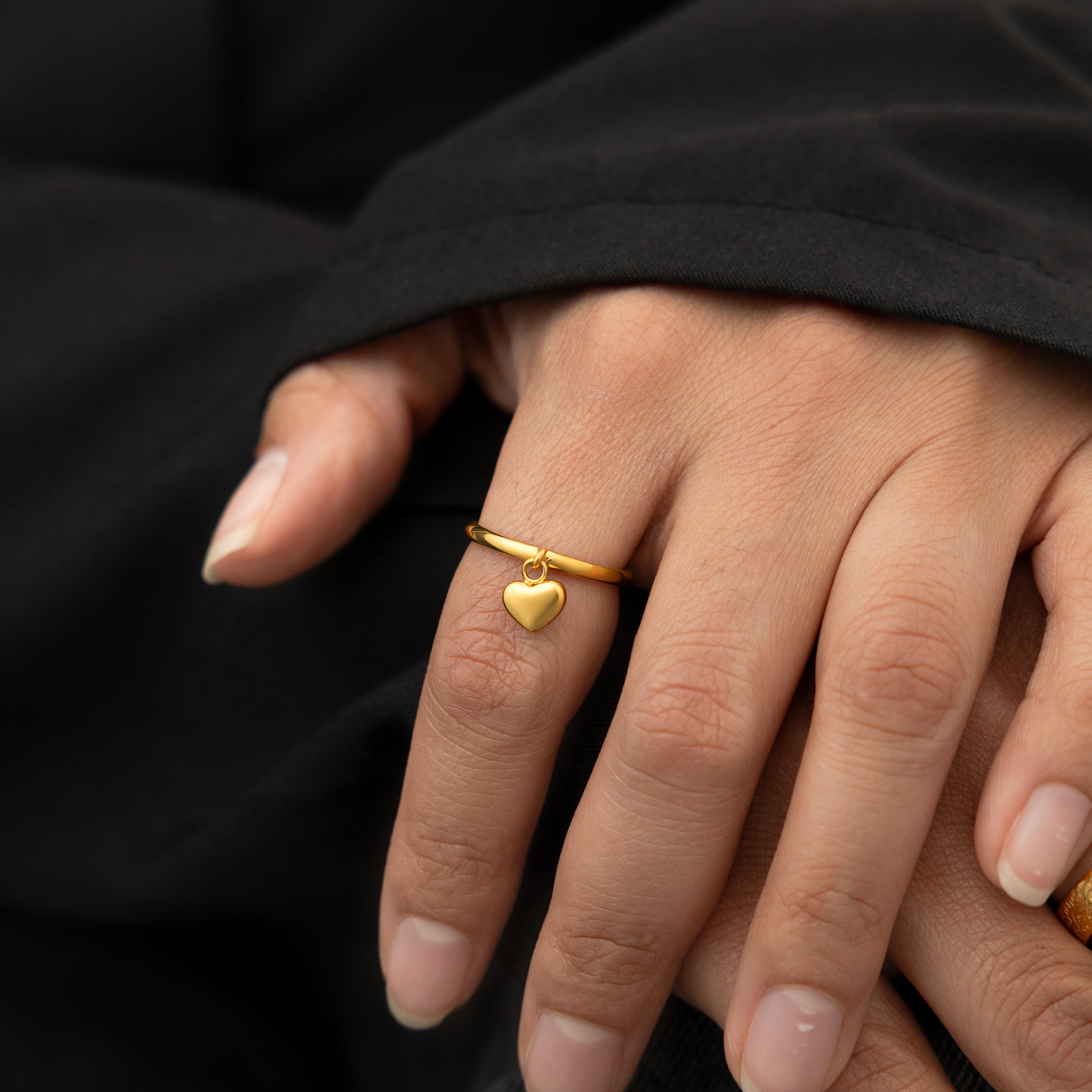 Close-up of the heart charm on the gold loop ring, highlighting the craftsmanship.