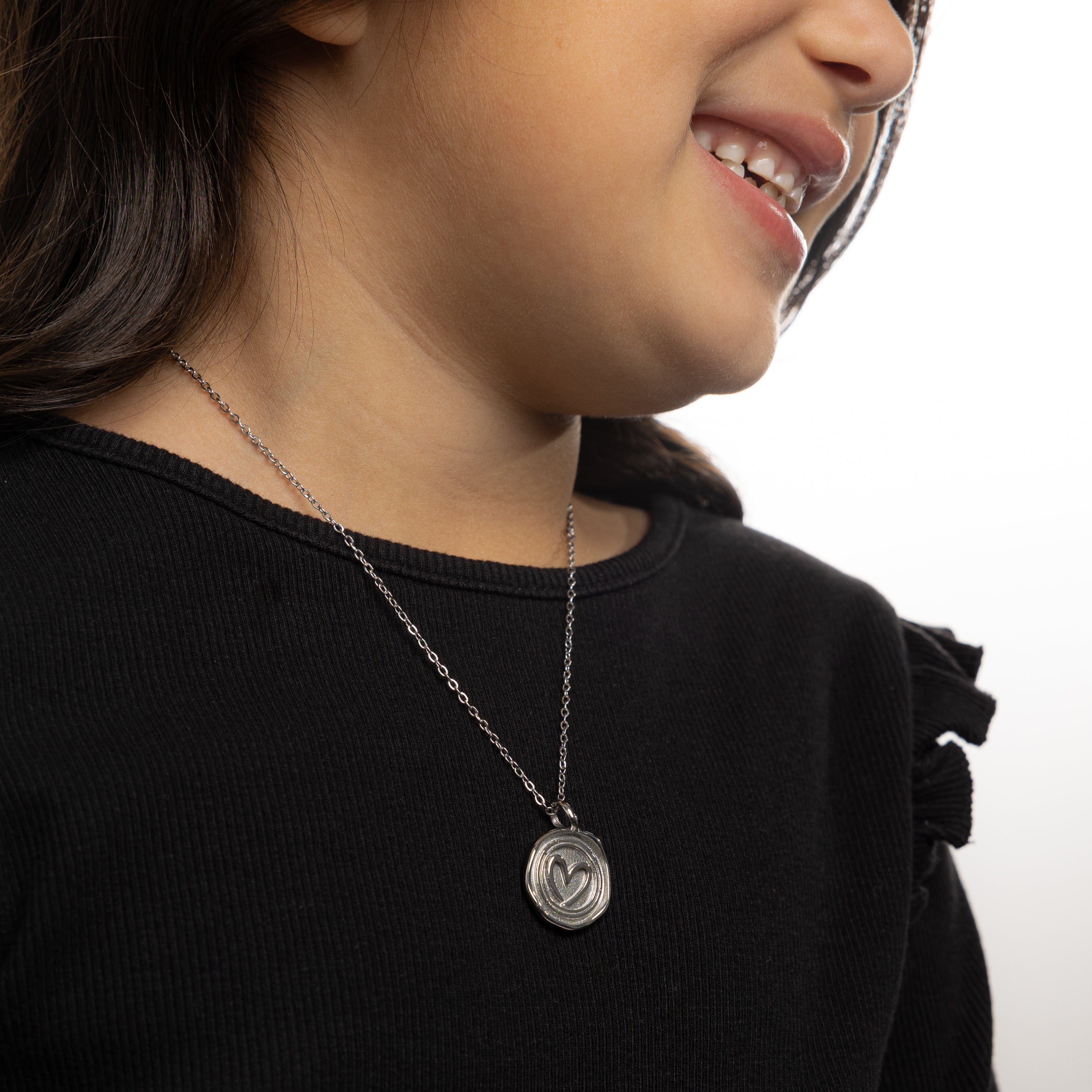 Close-up of personalized heart necklace gift in a velvet pouch.