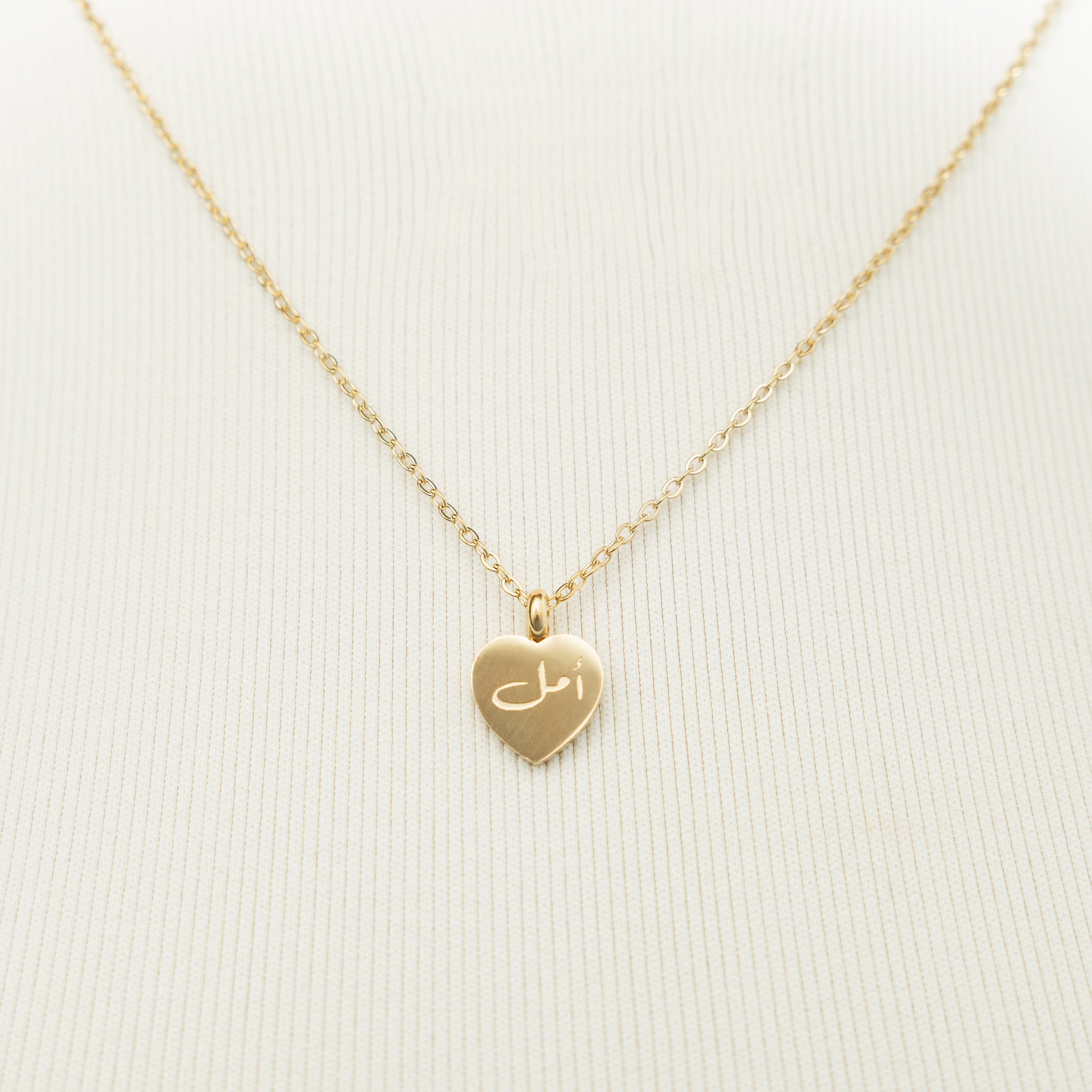 Close-up of the hope charm necklace, highlighting the 18K gold plating and hope pendant.