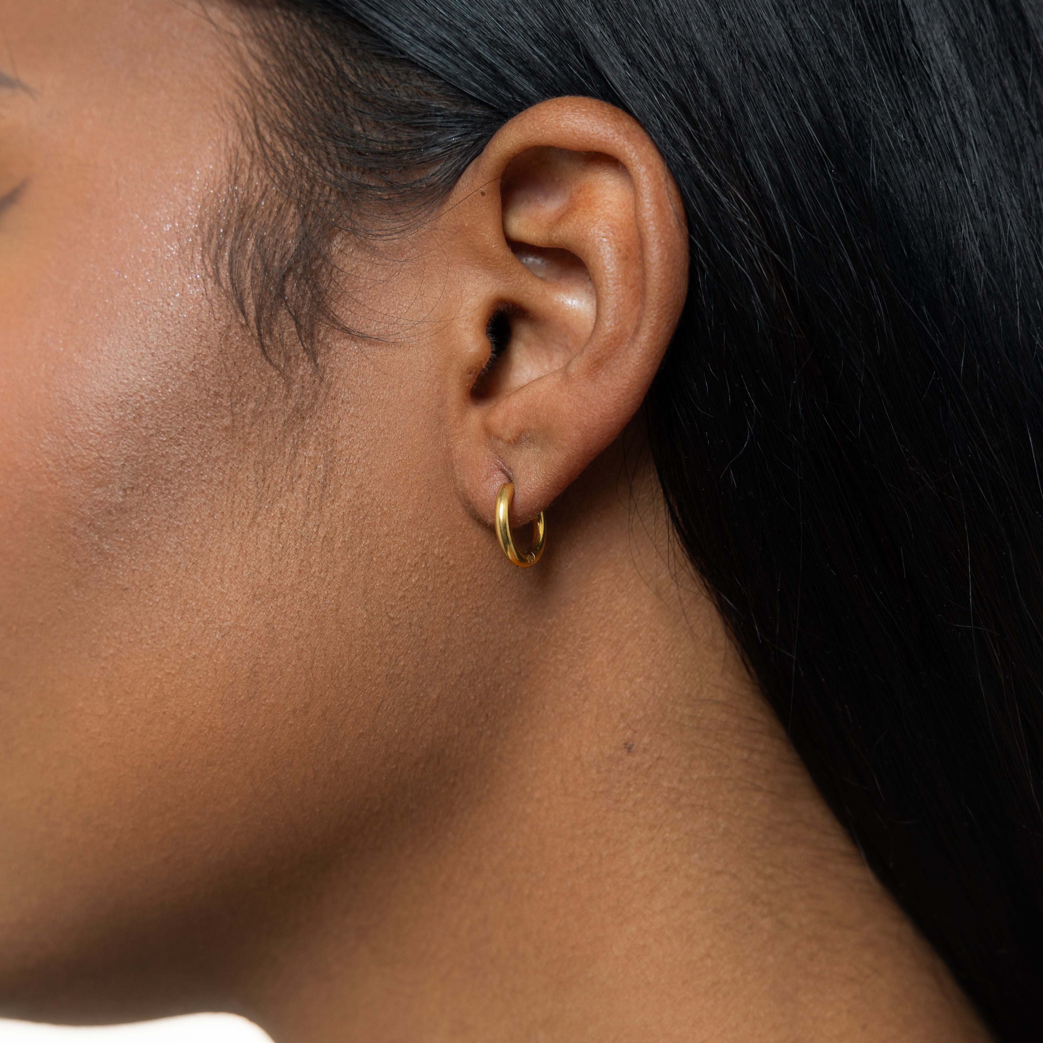 Essential 8mm gold huggie earrings in a close-up view showcasing the delicate design and 18 Karat gold plating.