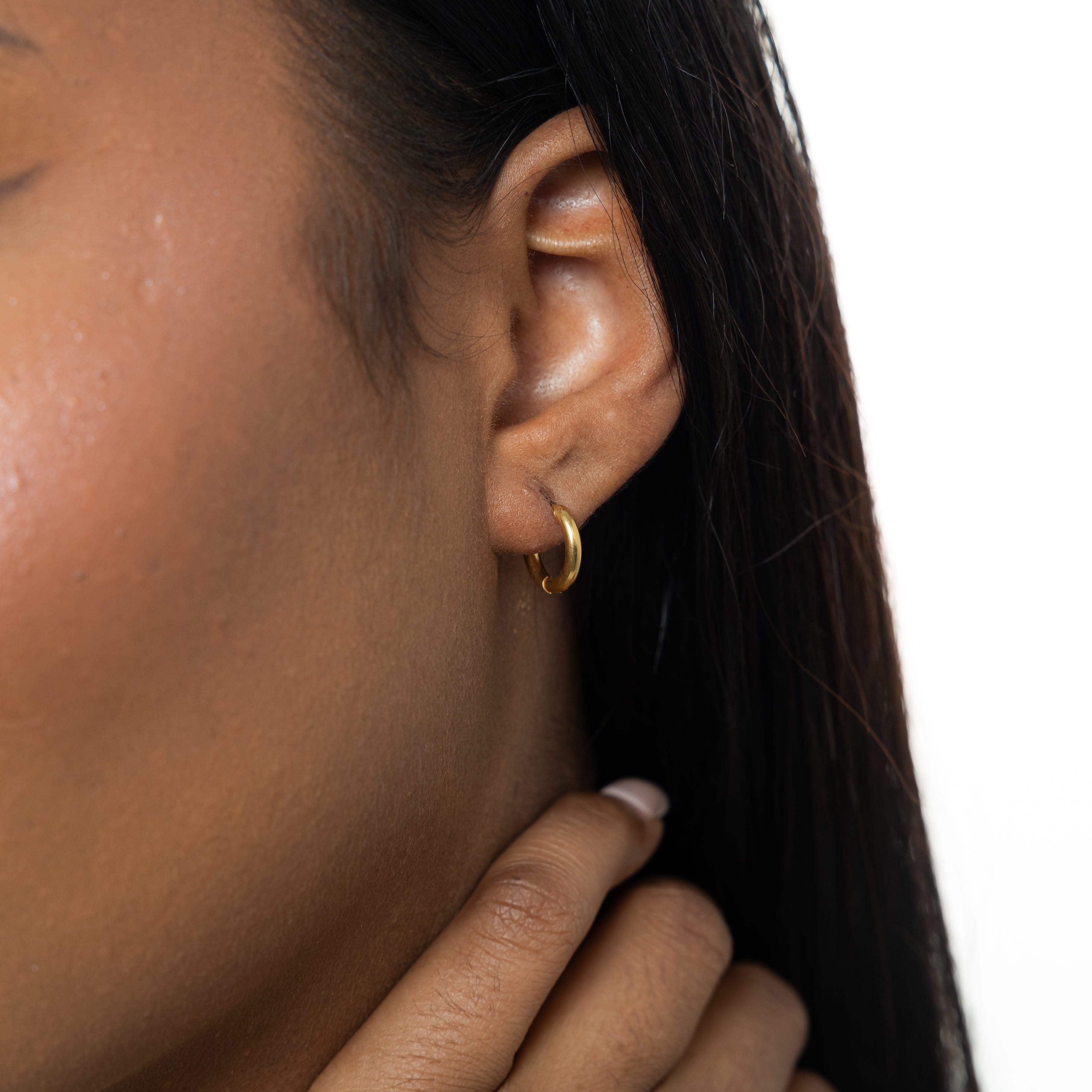 Waterproof gold huggie earrings for women displayed on a clean, minimalist background to emphasize their elegant, small hoop design.