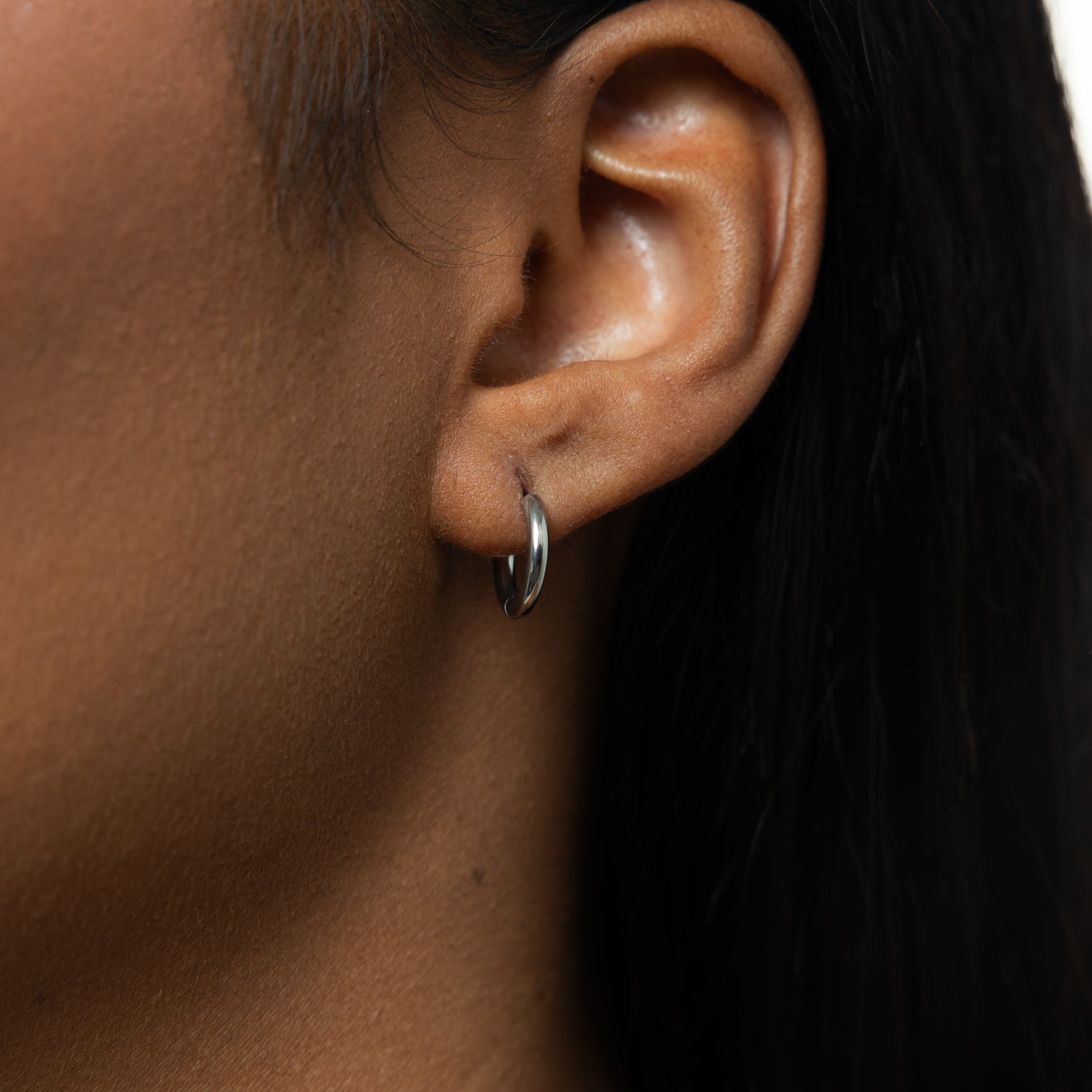 Essential 8mm gold huggie earrings in a close-up view showcasing the delicate design and 18 Karat gold plating.