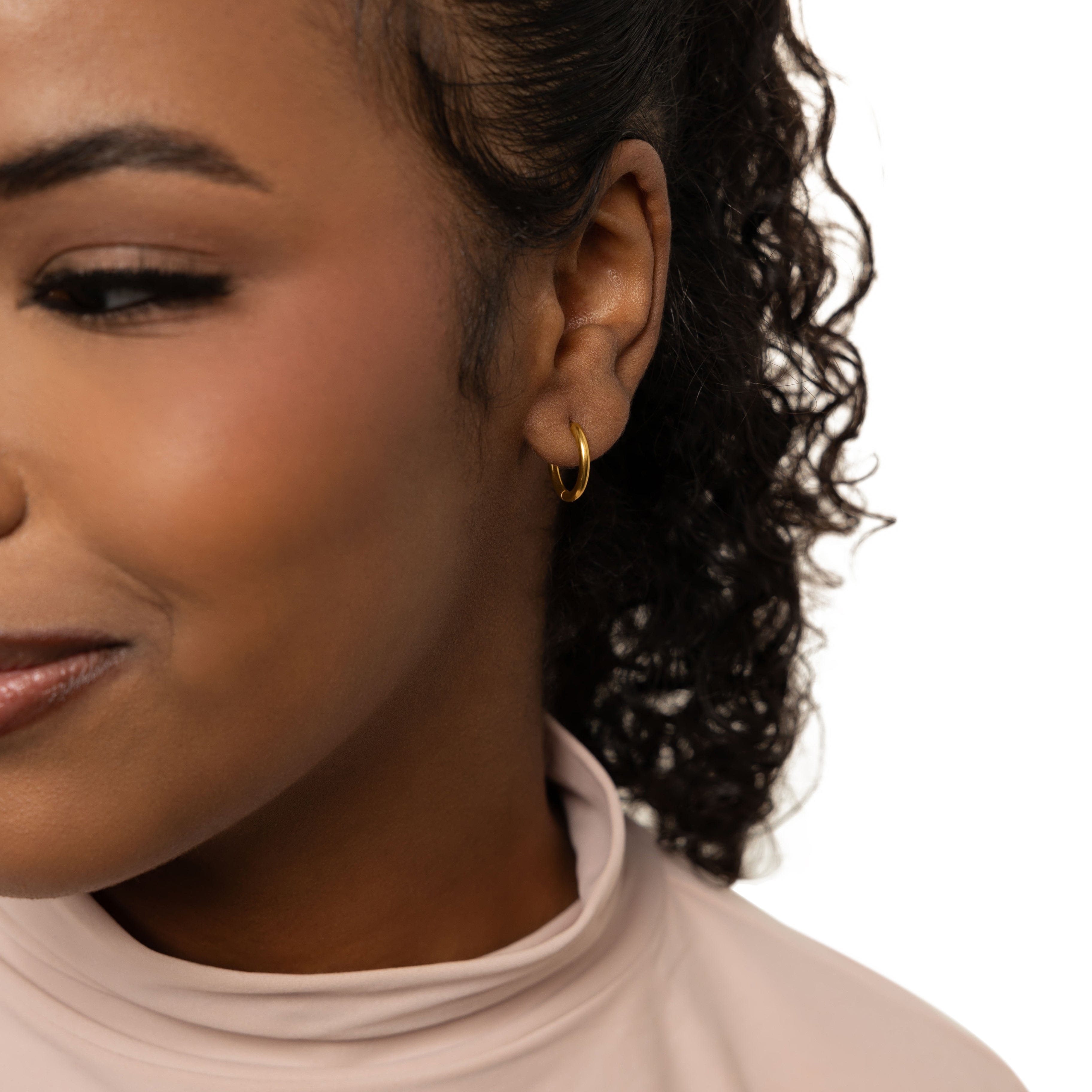 Chic 18K gold huggie earrings displayed on a models ear, showcasing their elegant design.