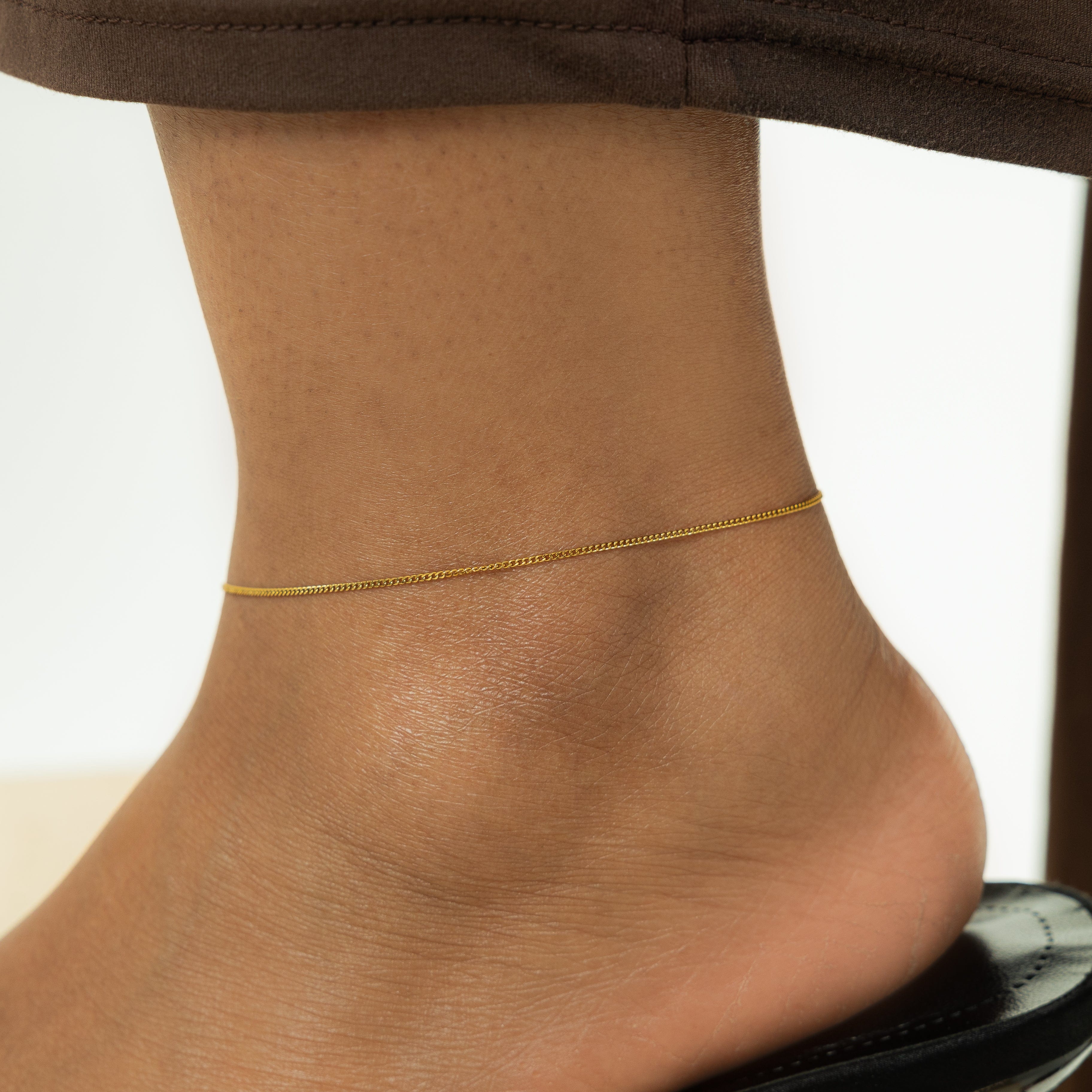 Close-up of the 1MM flat oval chain of the Invisible Curb Anklet, highlighting its gold plating.