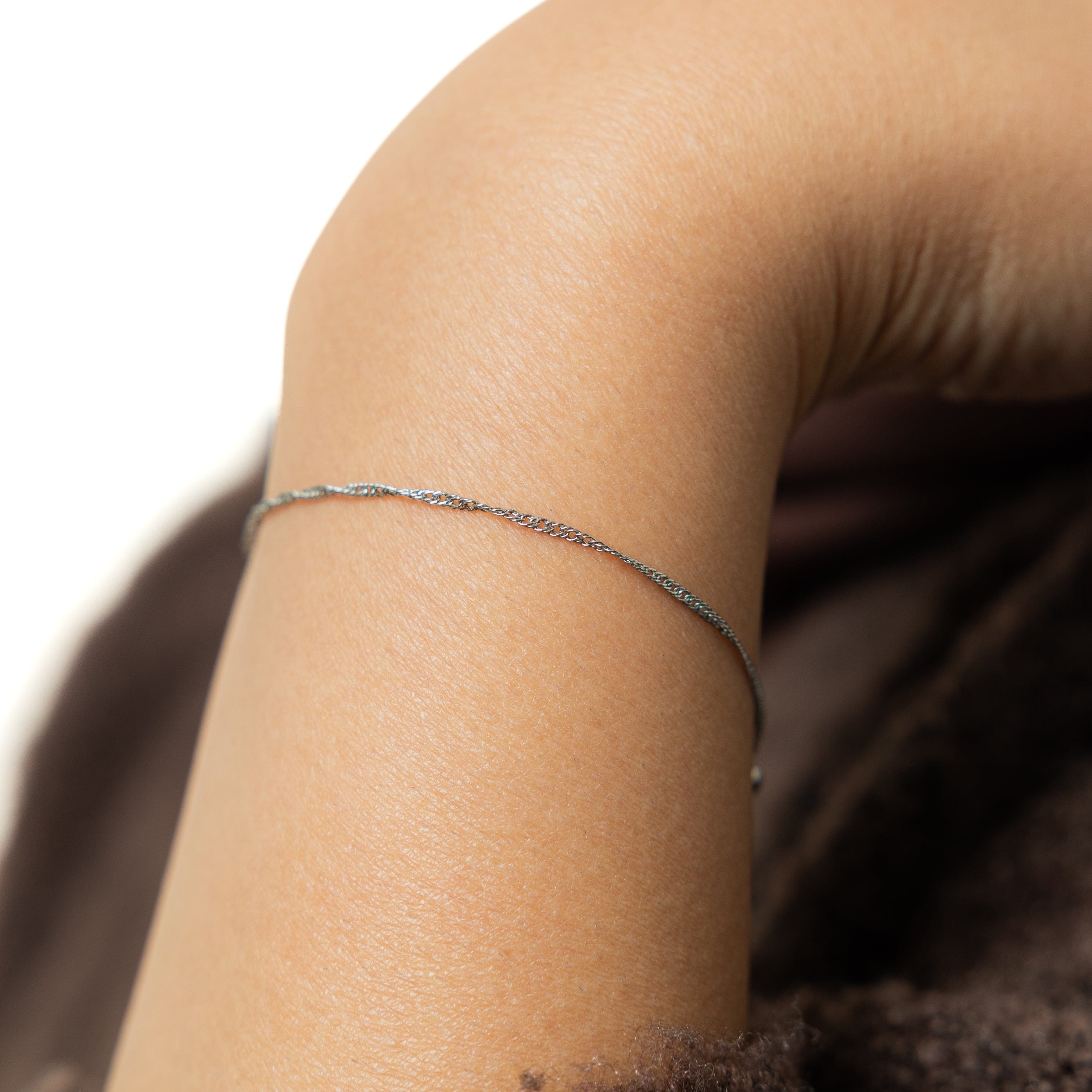 Elegant twisted gold bracelet showcasing its delicate chain design.