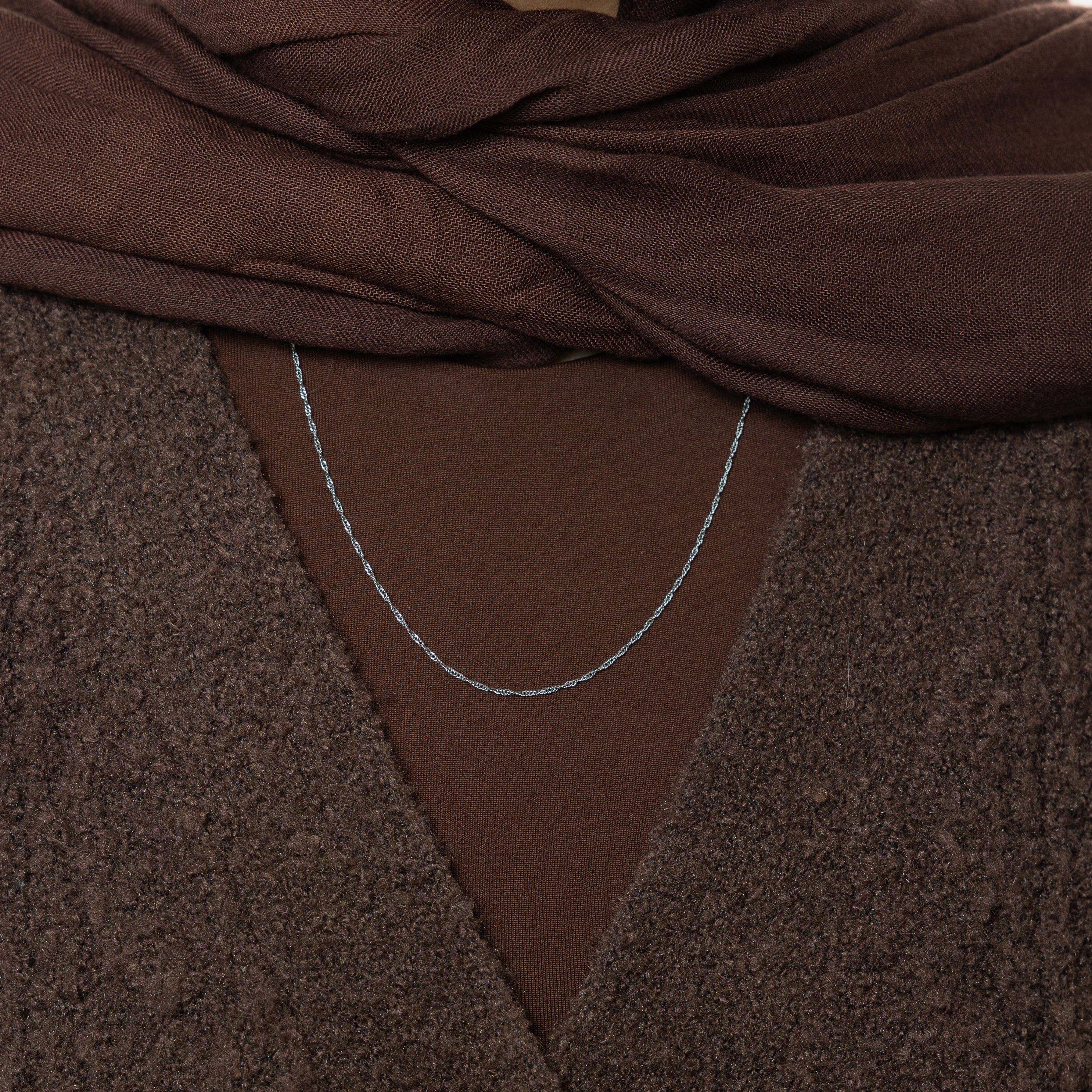 The gold twisted chain necklace styled with casual and formal outfits, illustrating its versatility.