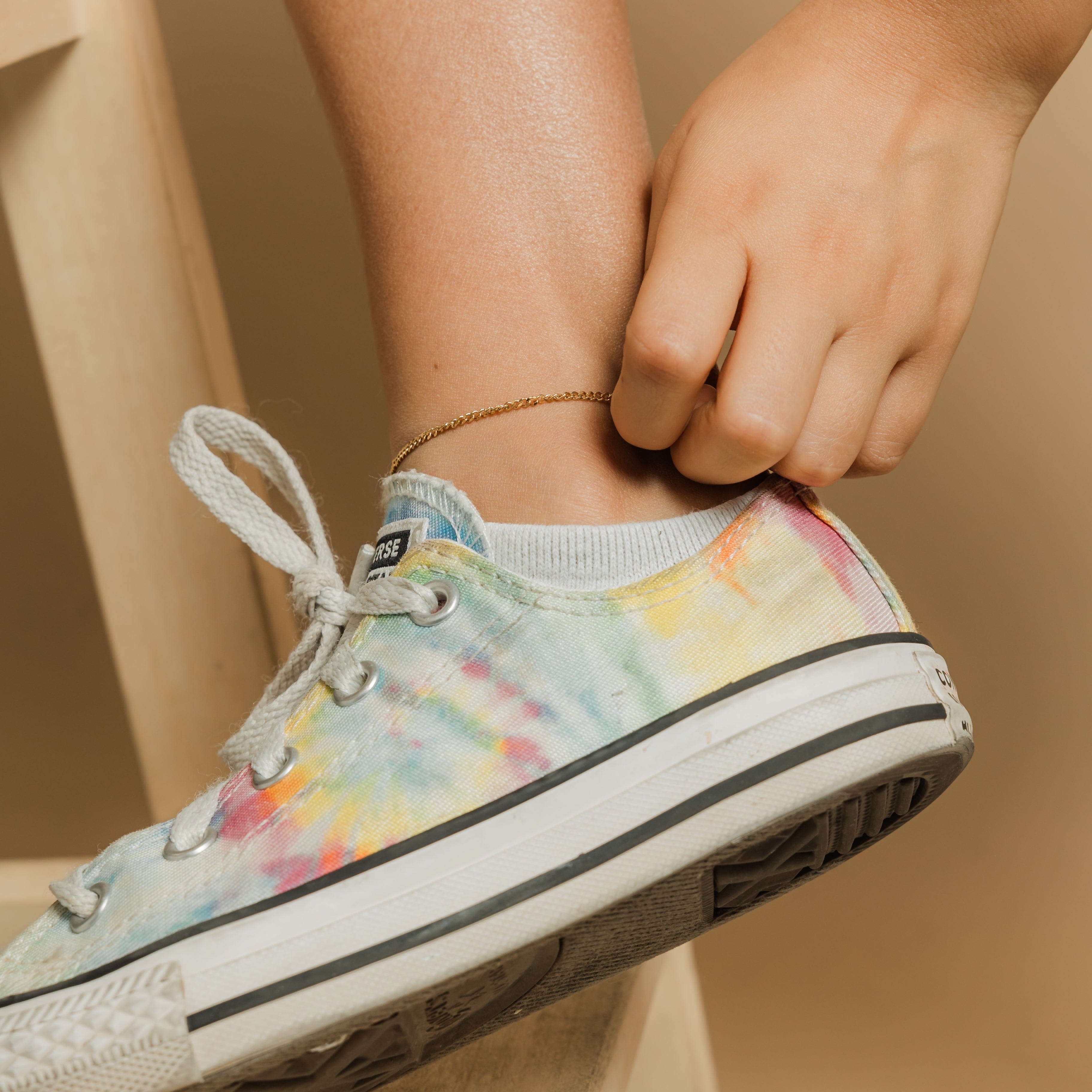 The gold Cuban chain anklet displayed in a velvet pouch