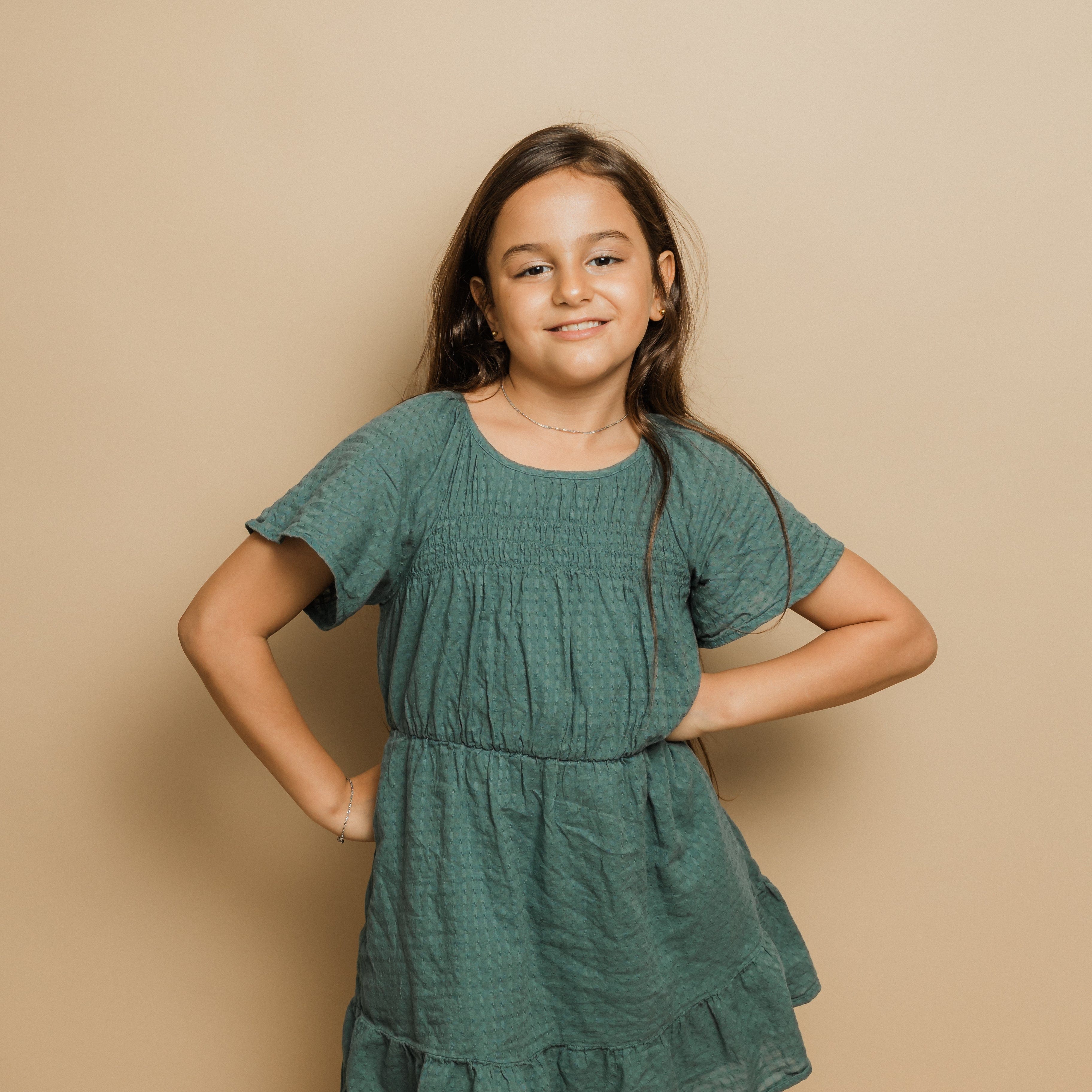 A young girl wearing the hypoallergenic bracelet, smiling confidently at a sunny outdoor event.